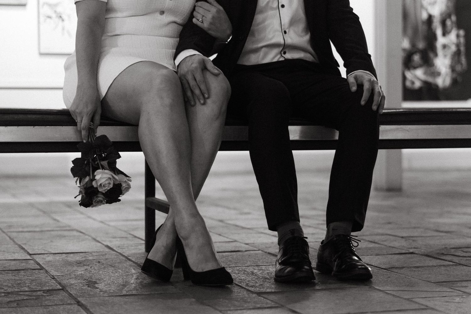 Close-up of a seated couple's legs with a small bouquet resting beside them.