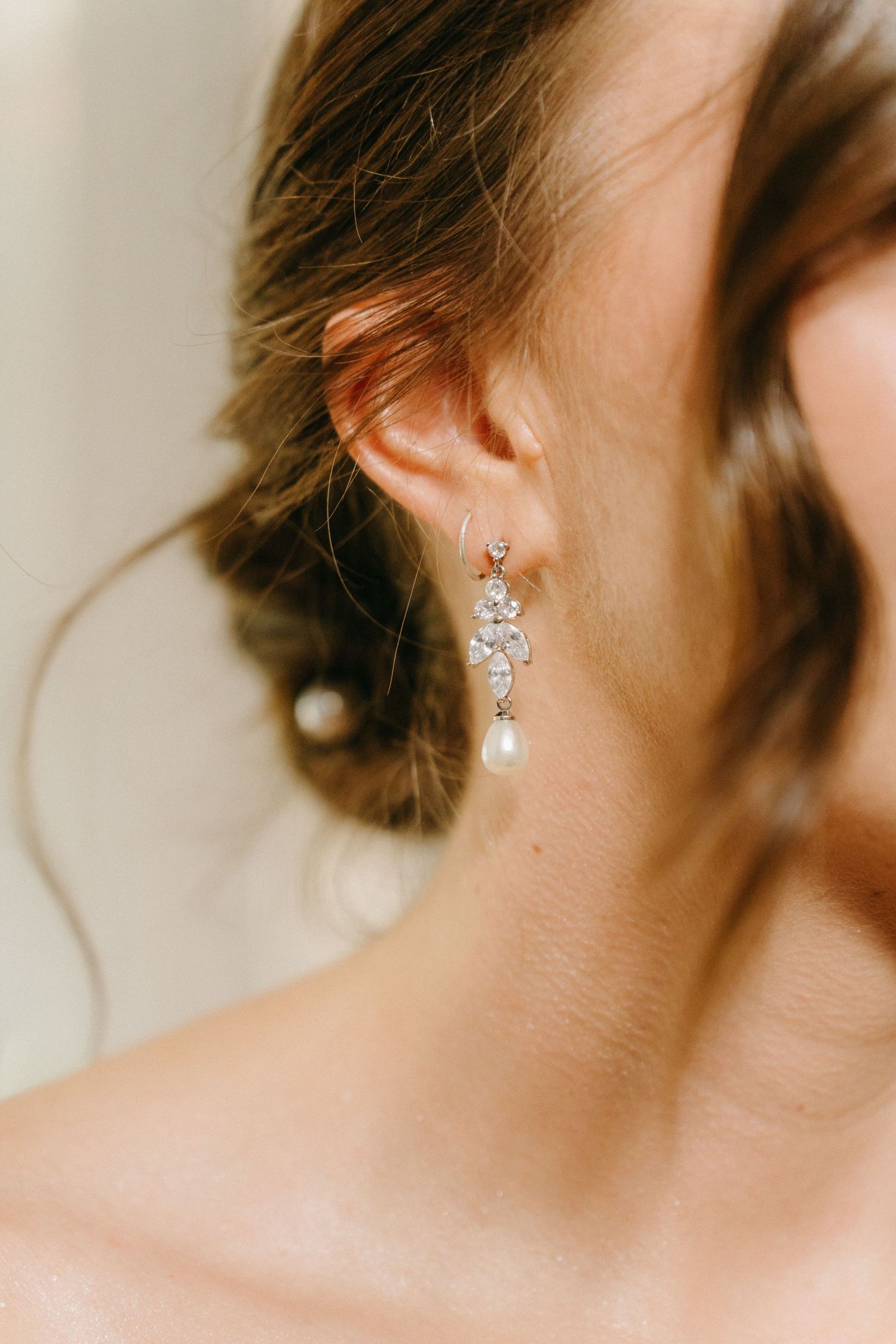 Delicate pearl and crystal bridal earring shown in closeup against soft natural light.