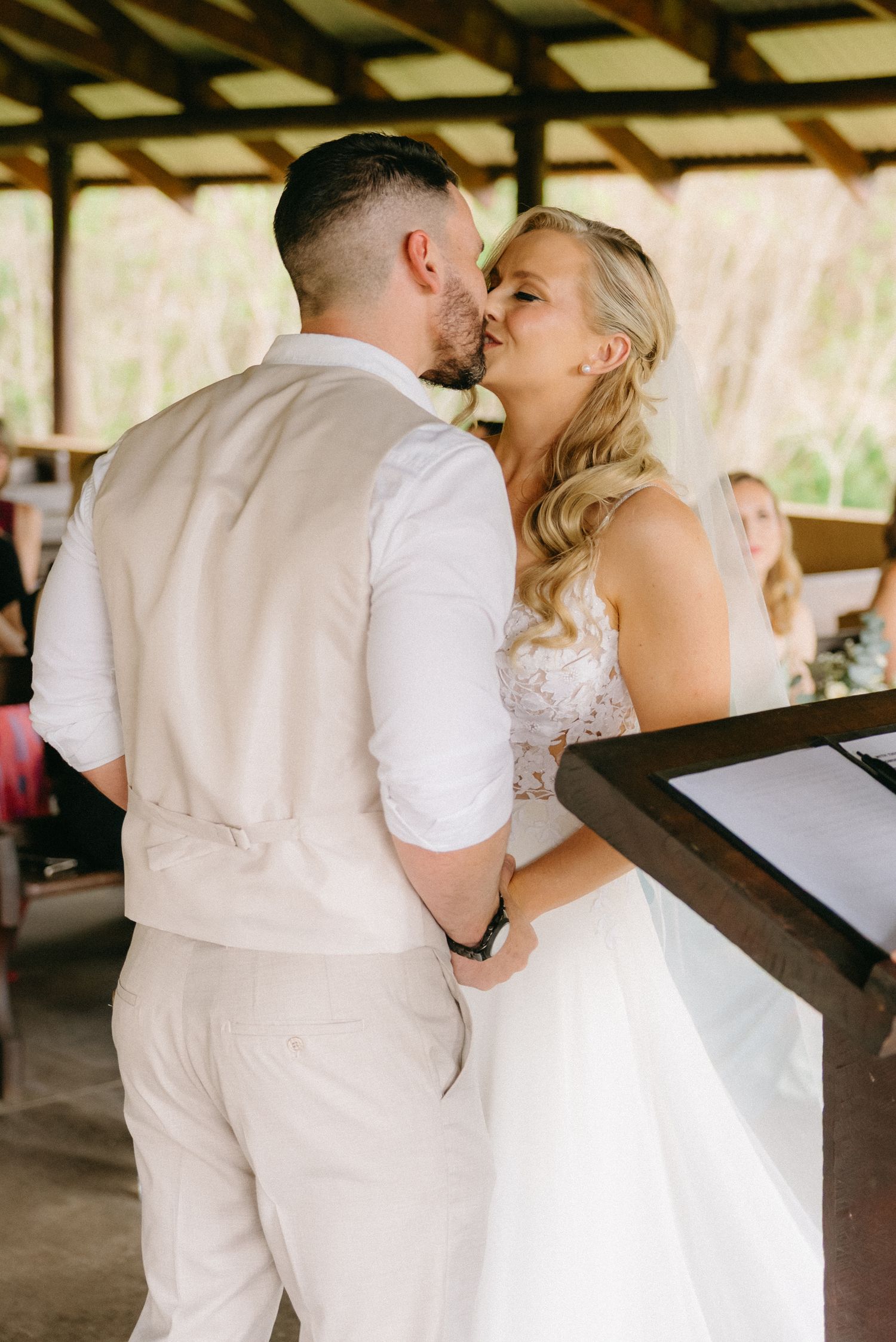 A couple shares their first dance under a wooden pavilion.