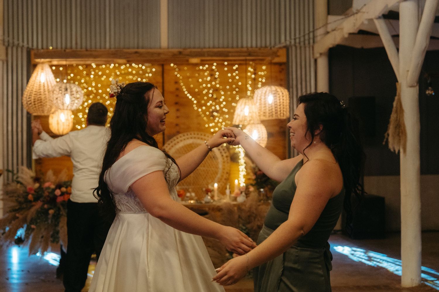 Wedding celebration dance party with twinkle lights creating warm ambiance in rustic venue.