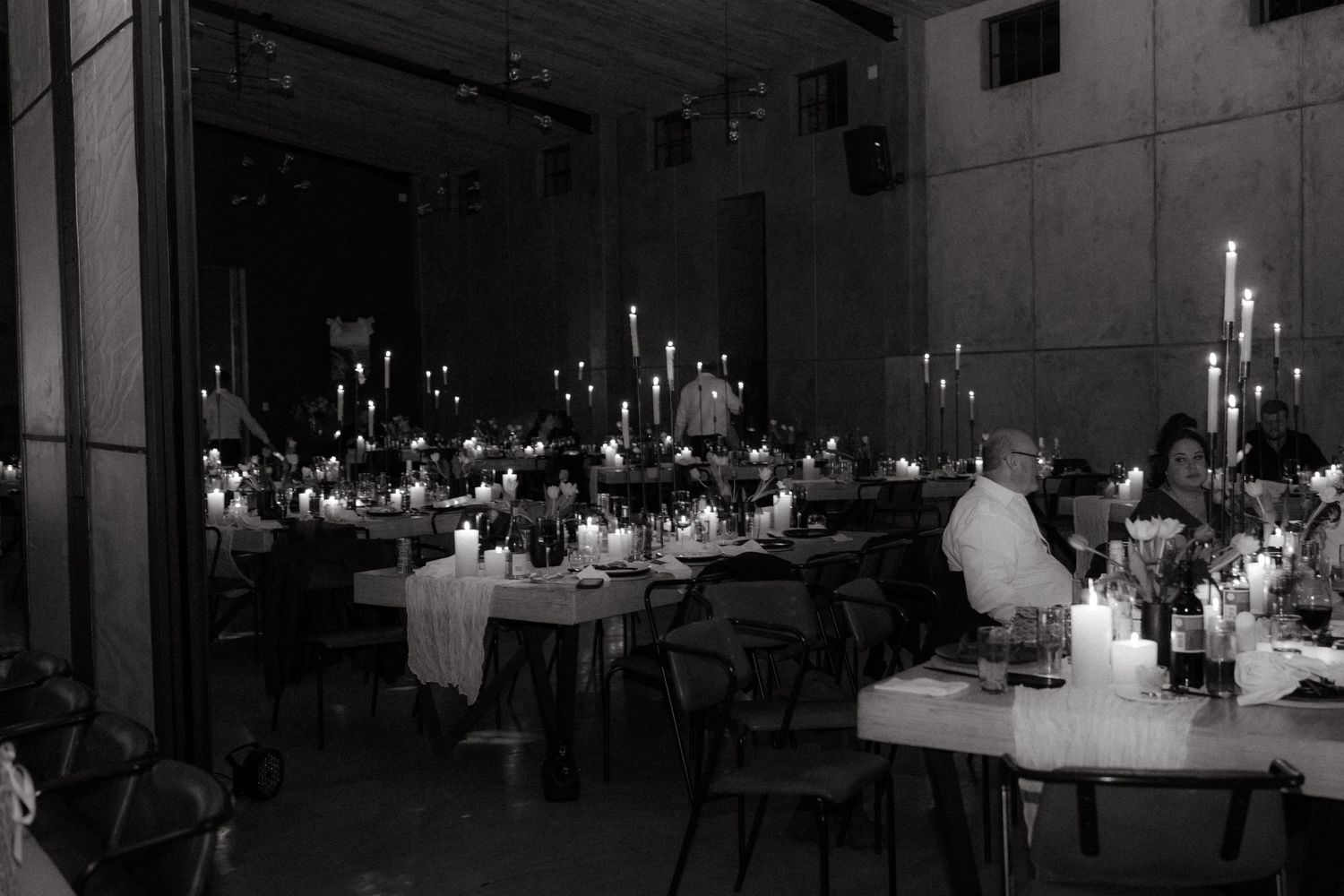 Black and white photo of an elegant wedding reception with candlelit tables and romantic ambiance.