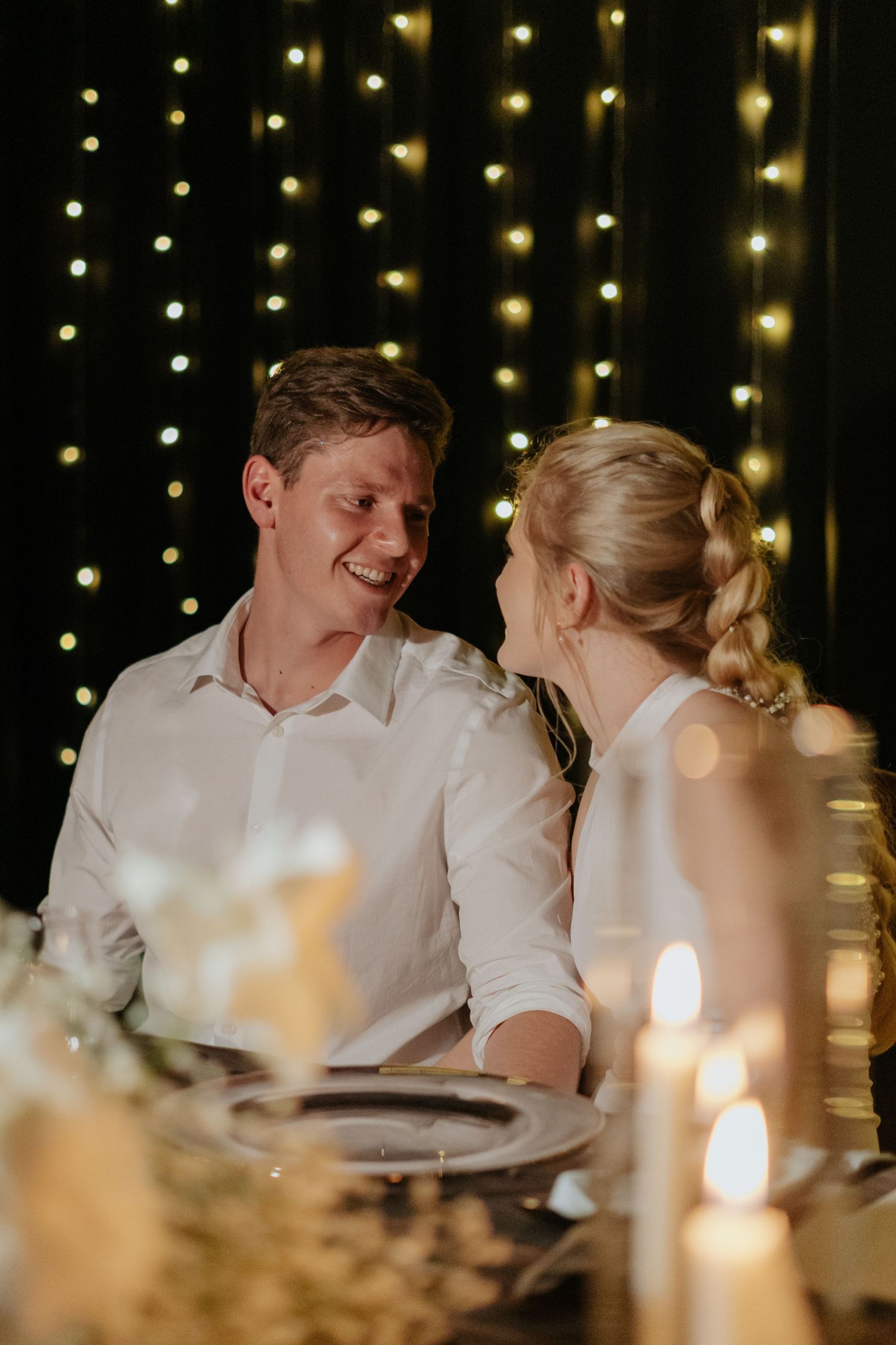 Romantic candlelit dinner scene with string lights twinkling in the background.