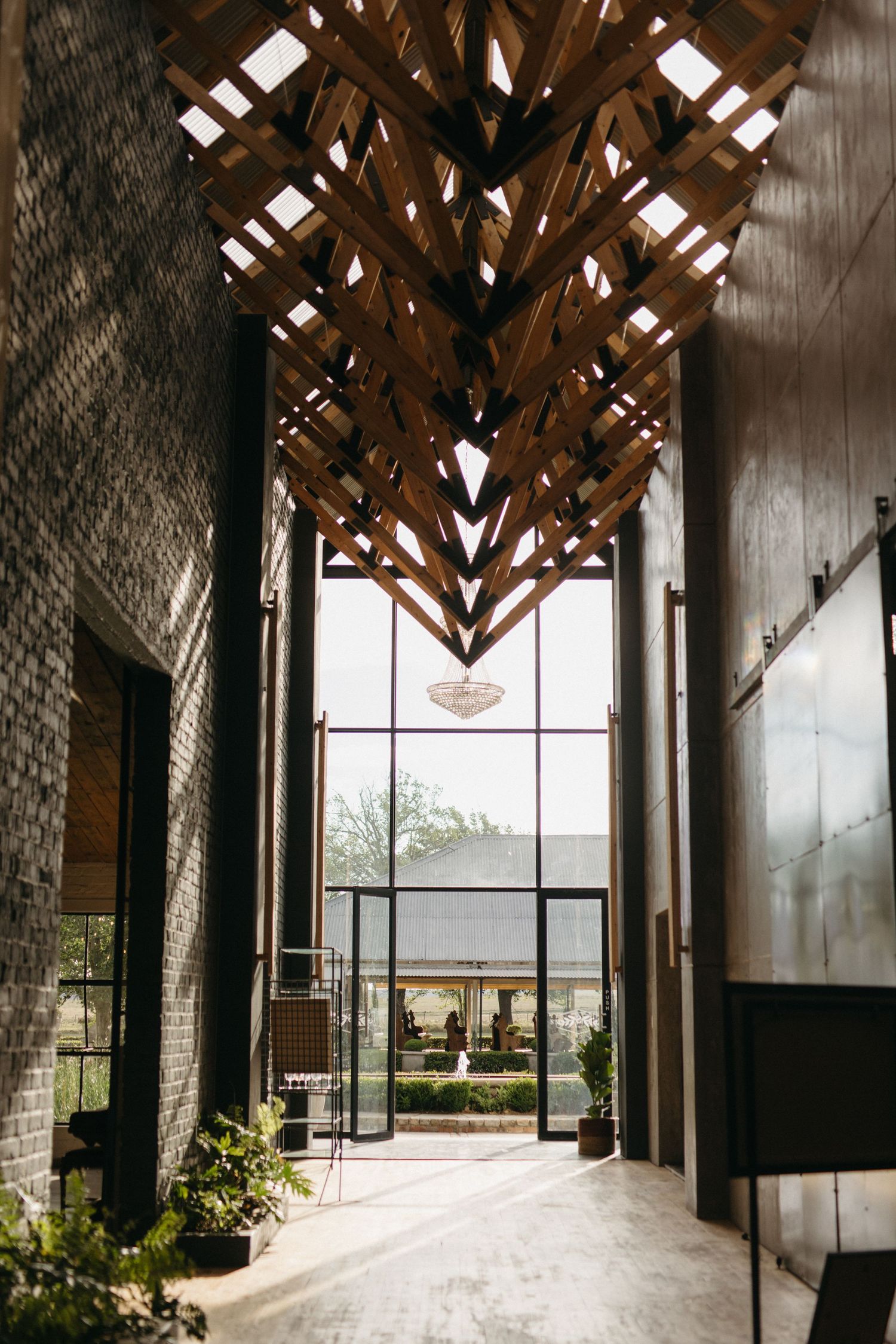 Modern architectural hallway with dramatic wooden beam ceiling design and glass windows letting in natural light.
