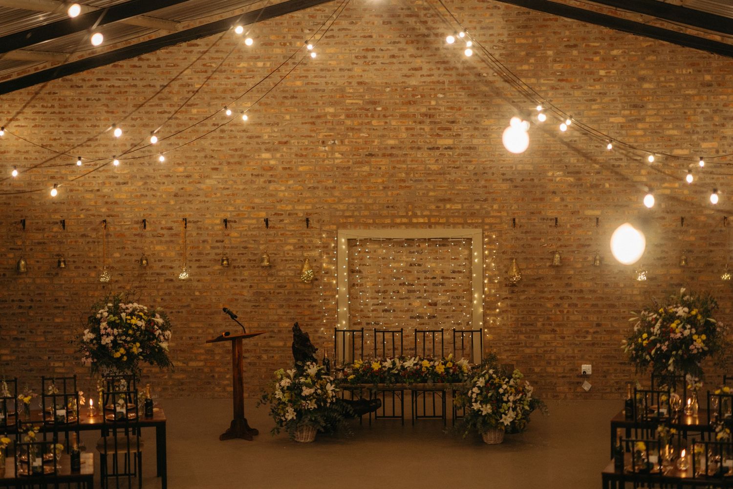 Rustic brick wedding venue with string lights and floral arrangements creating a romantic ambiance.