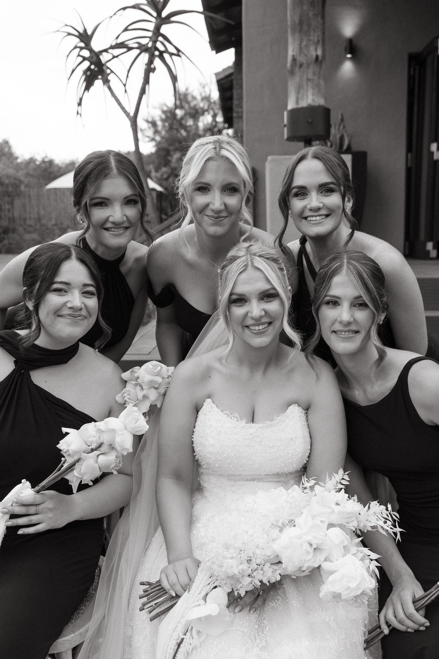 Black and white wedding party photos showing joyful group poses with bridesmaids and bride in white dress.