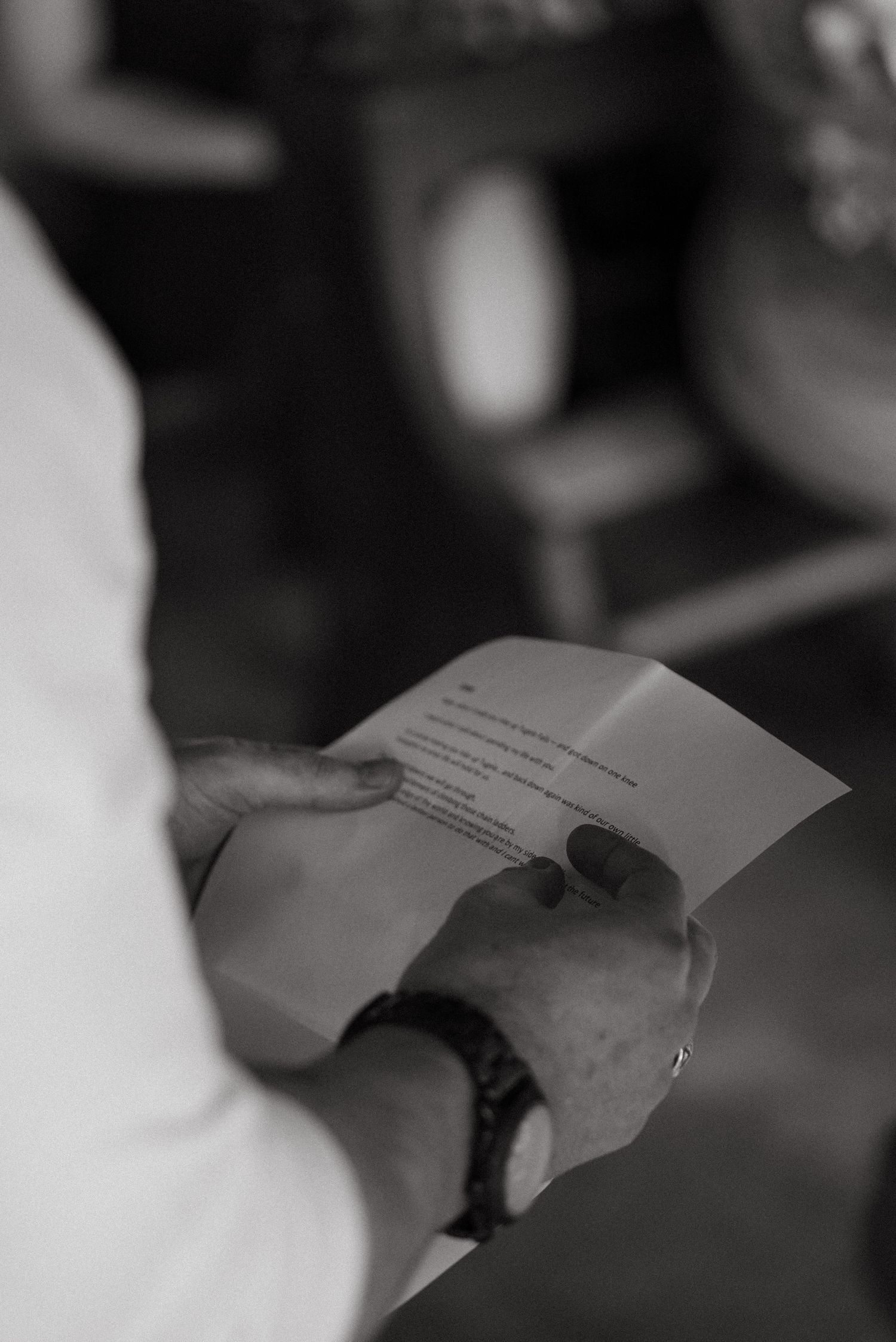 Black and white close-up shot of hands holding wedding ceremony papers.