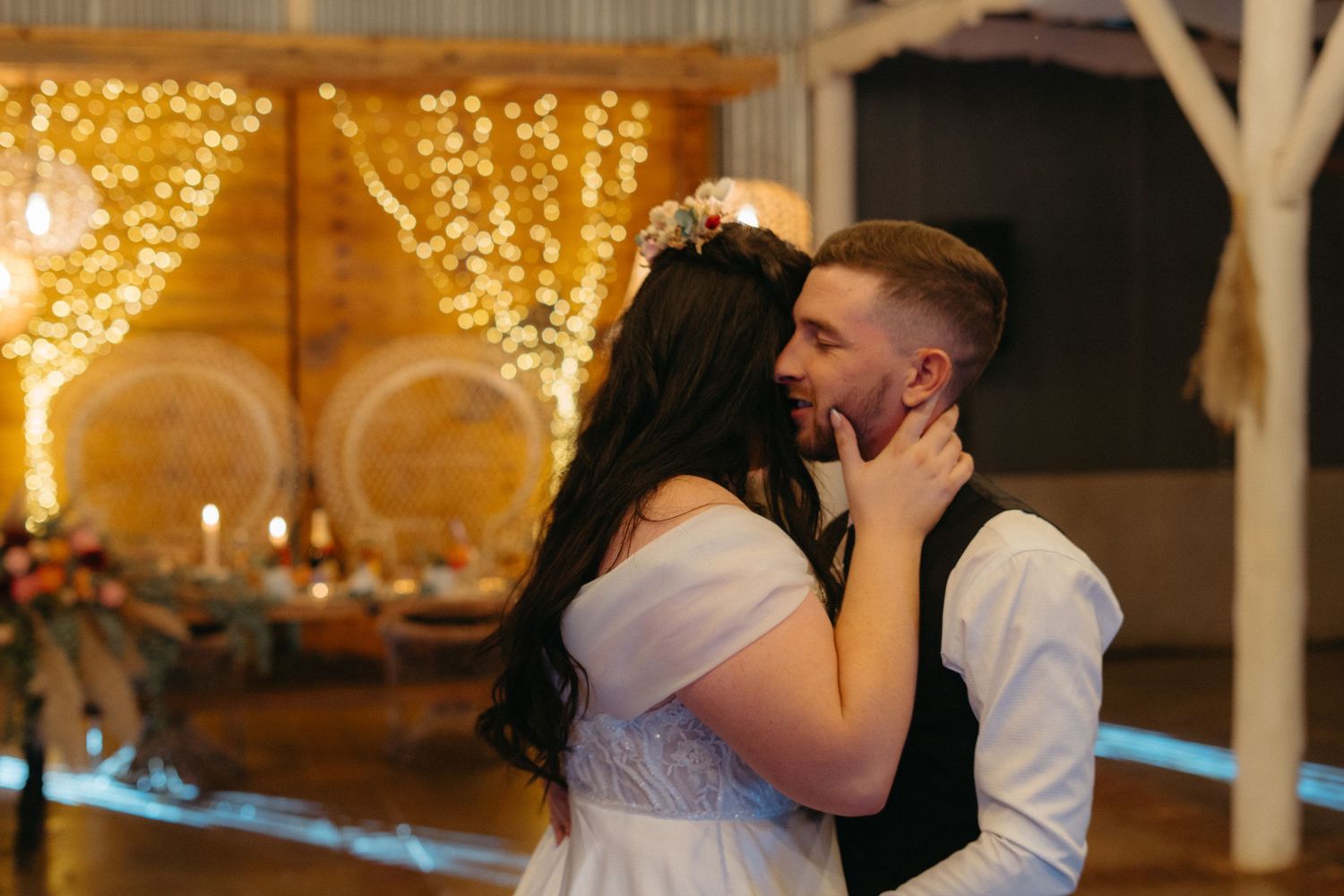 A romantic dance moment in a rustic barn venue decorated with warm glowing string lights.
