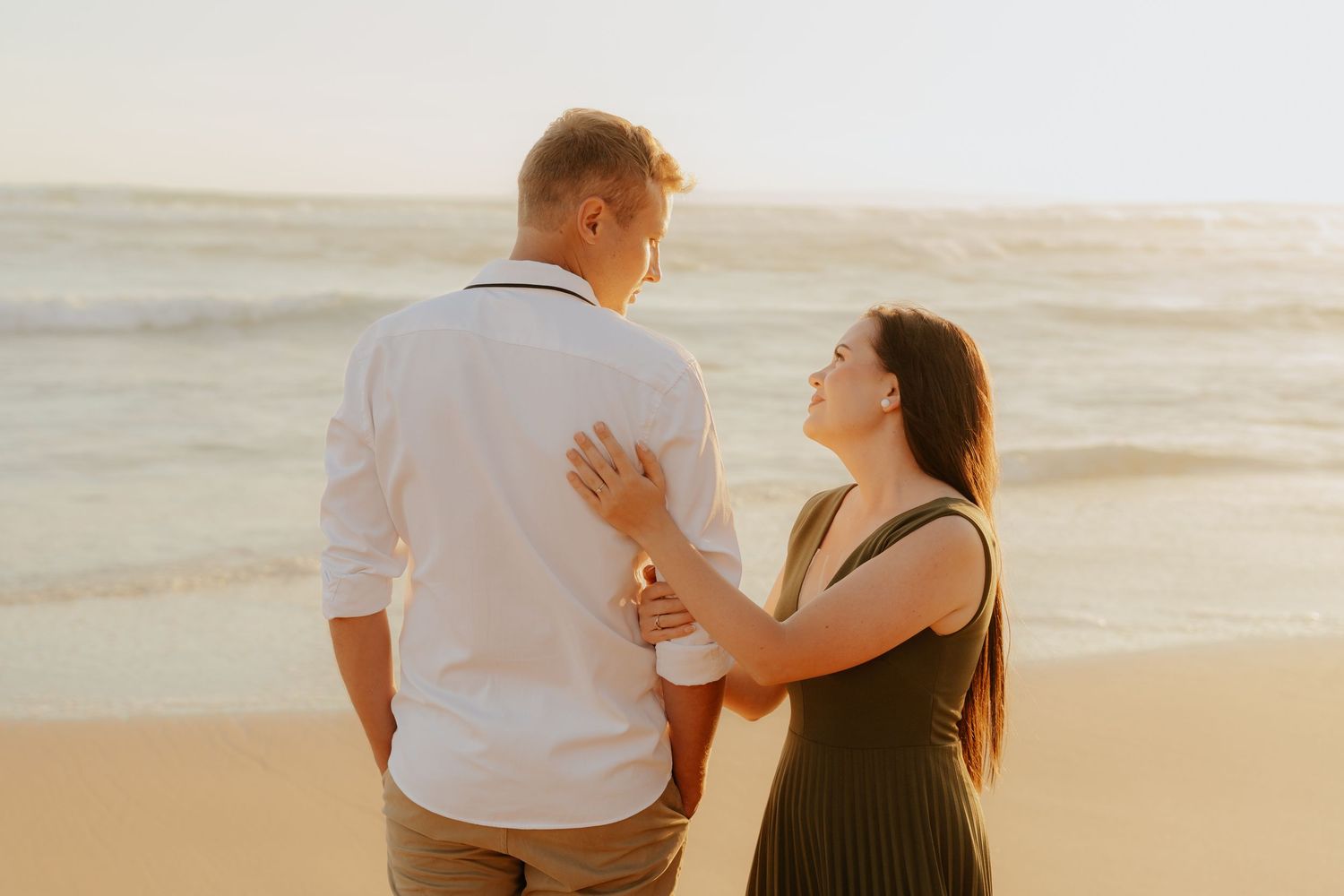 A couple walks together on a sandy beach at sunset in the warm golden light of the Garden Route