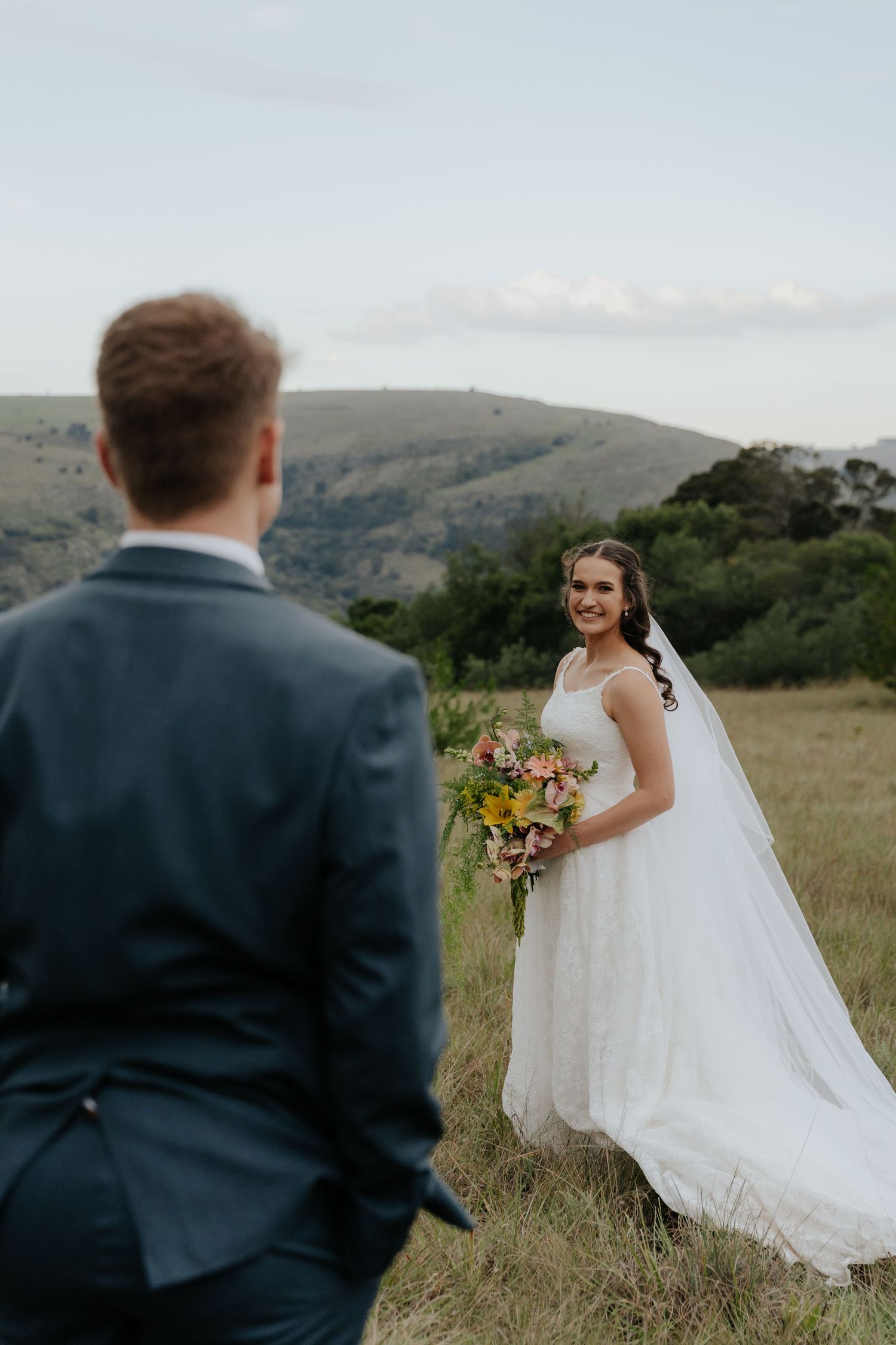 A couple shares a romantic moment in a scenic mountain meadow during their outdoor wedding ceremony.
