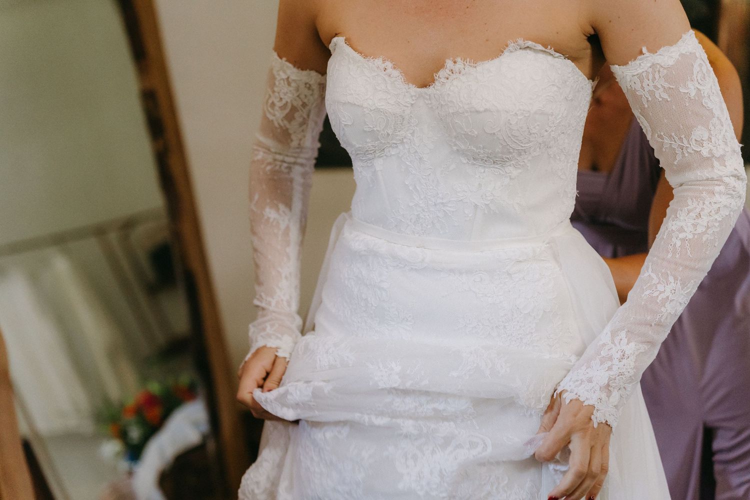 Close-up detail of a strapless lace wedding dress with long sleeves.