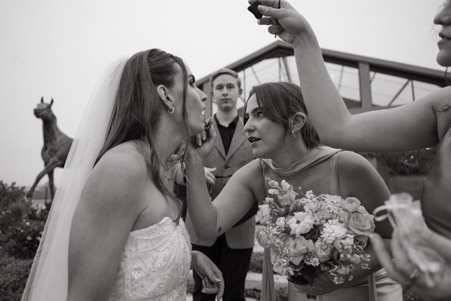 Black and white photo of bride and bridesmaid sharing emotional moment at outdoor wedding ceremony with guests at Tafika Polo Farm.