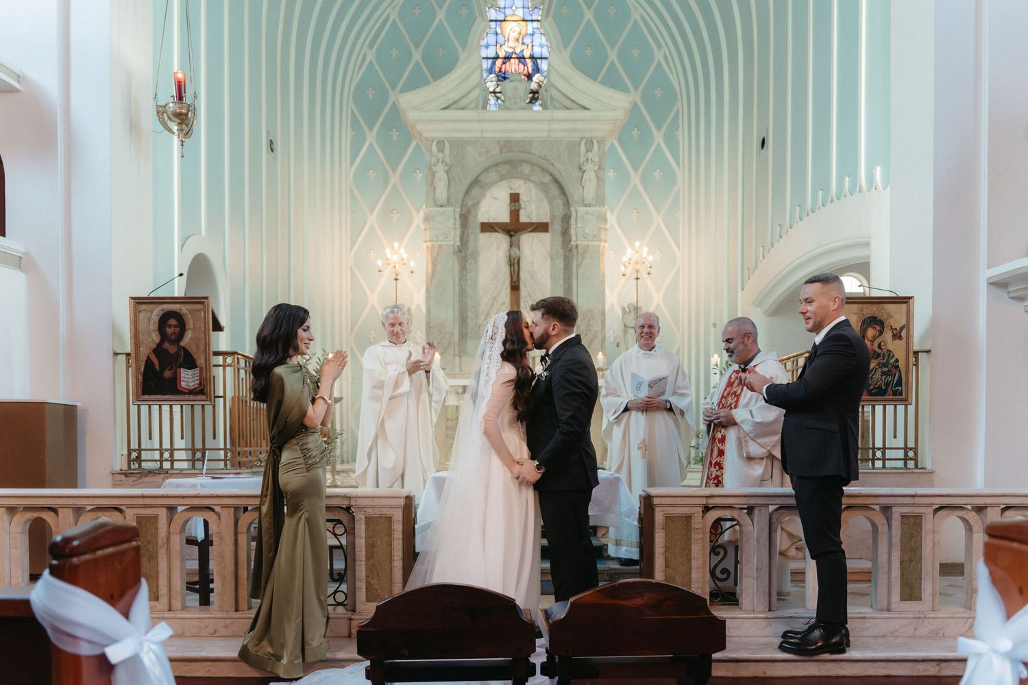Elegant church wedding ceremony with bride and groom at the altar, surrounded by wedding party in a white and mint interior.