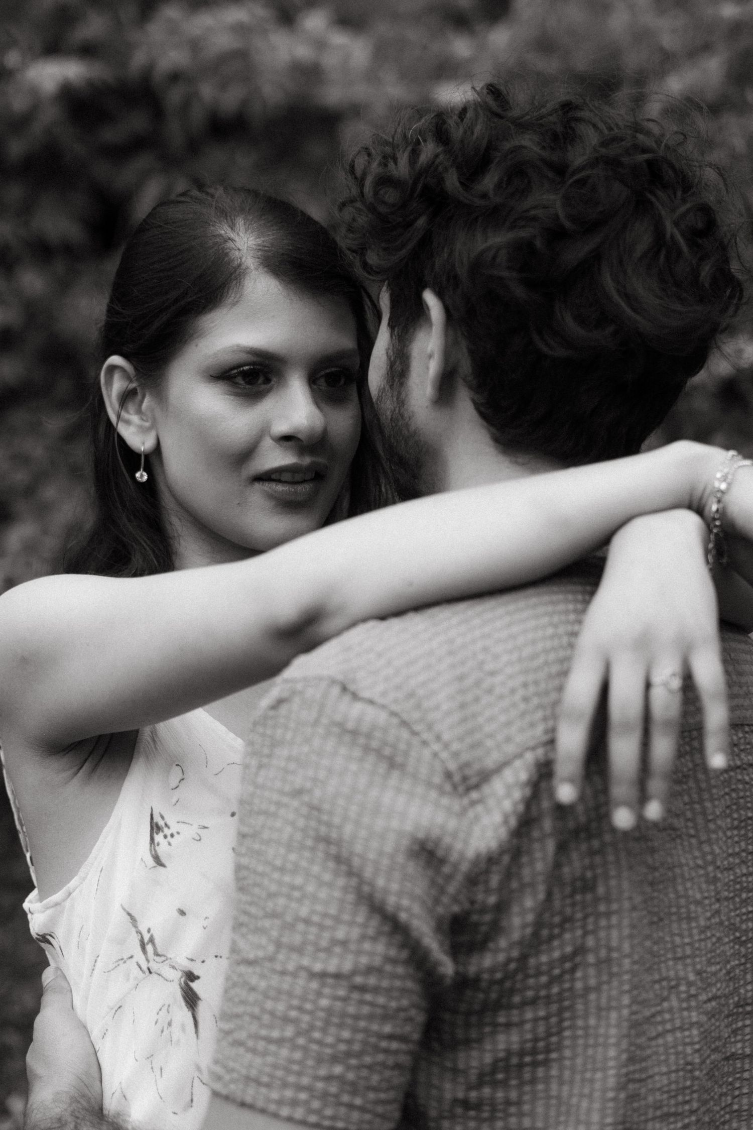 Black and white portrait of couple embracing in an intimate moment outdoors.