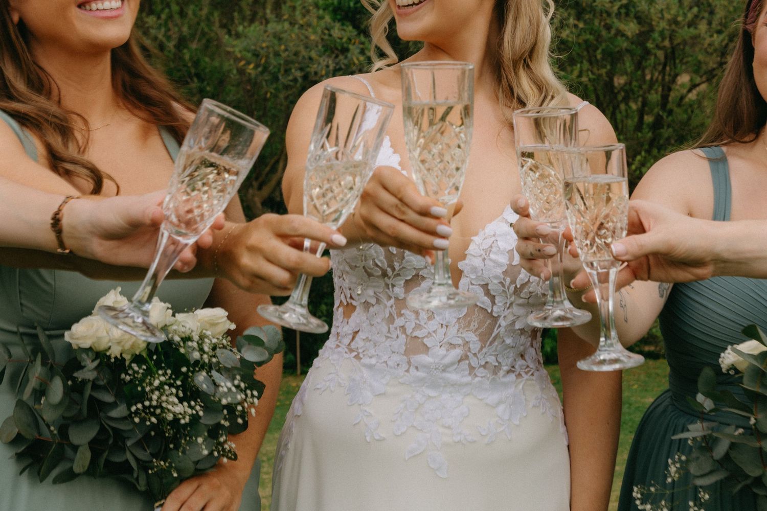 A group enjoying champagne toasts at an elegant outdoor celebration with floral arrangements and formal attire.