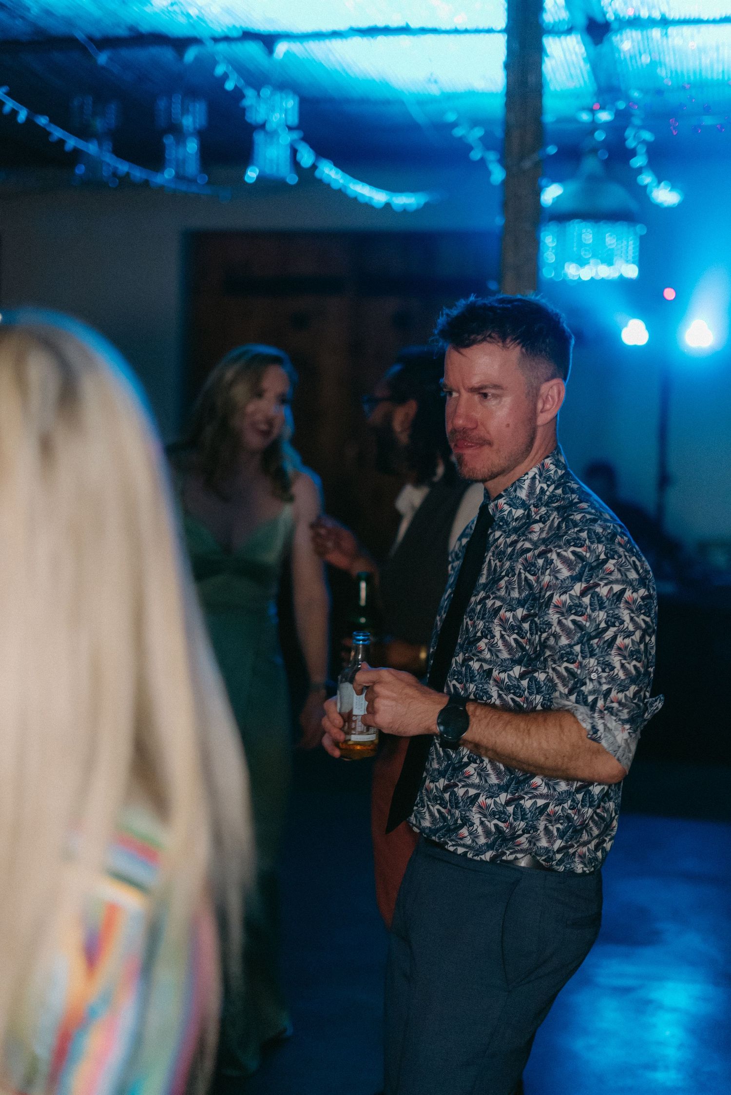 People dancing and celebrating at a reception with blue mood lighting.