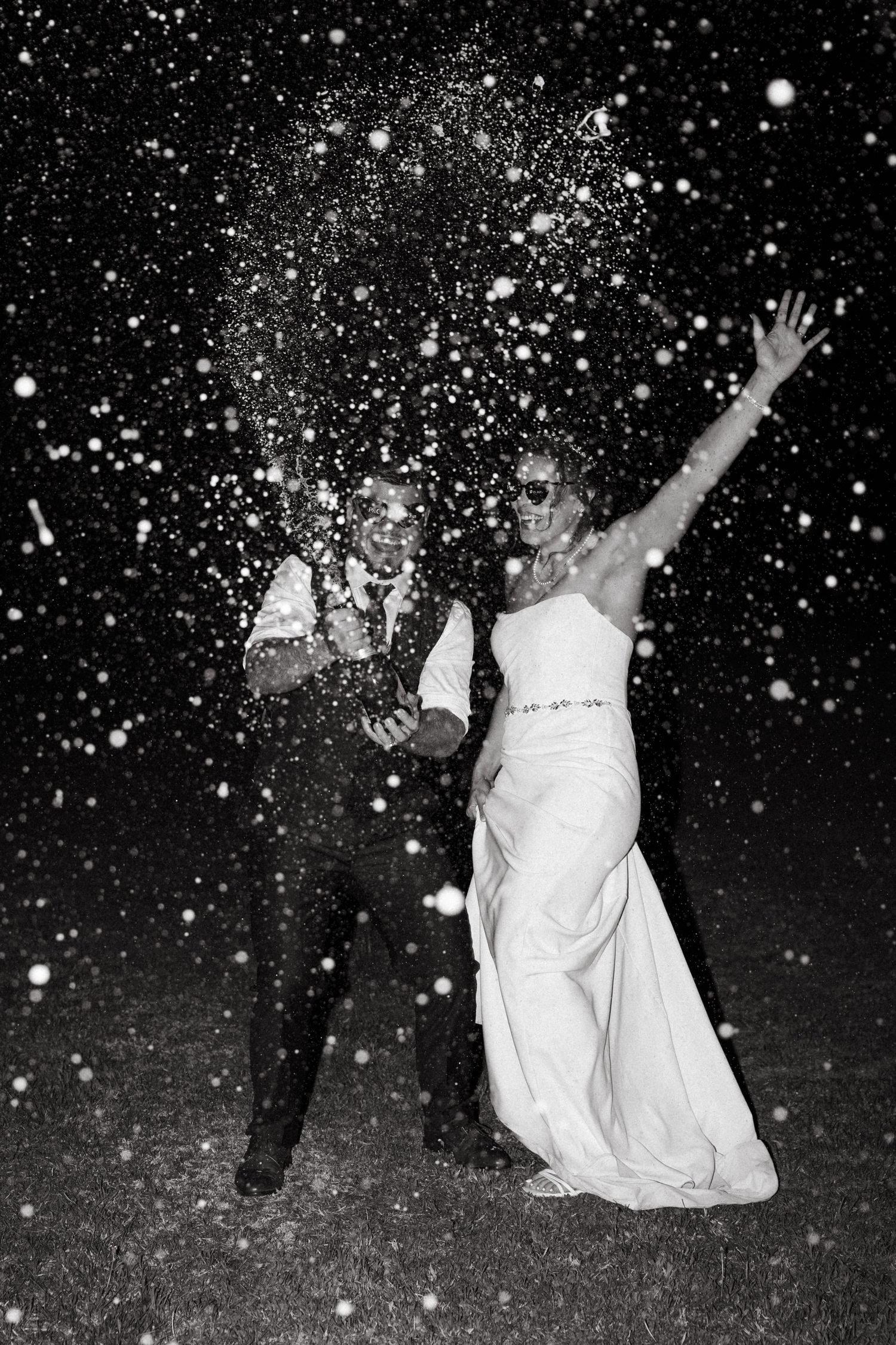 Black and white photo of a couple dancing in falling snow at night.