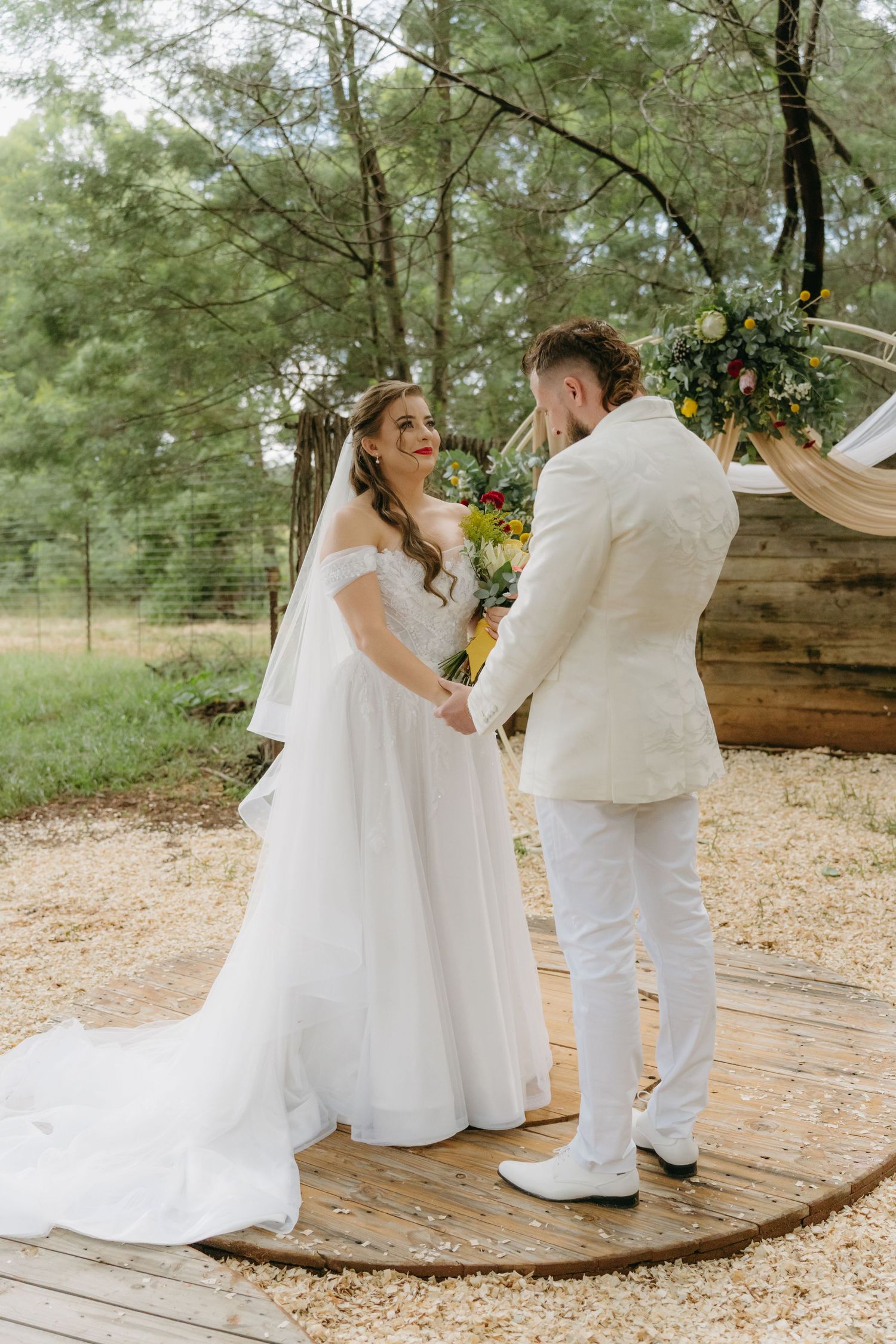 Bride and groom share intimate moment during outdoor woodland wedding ceremony.