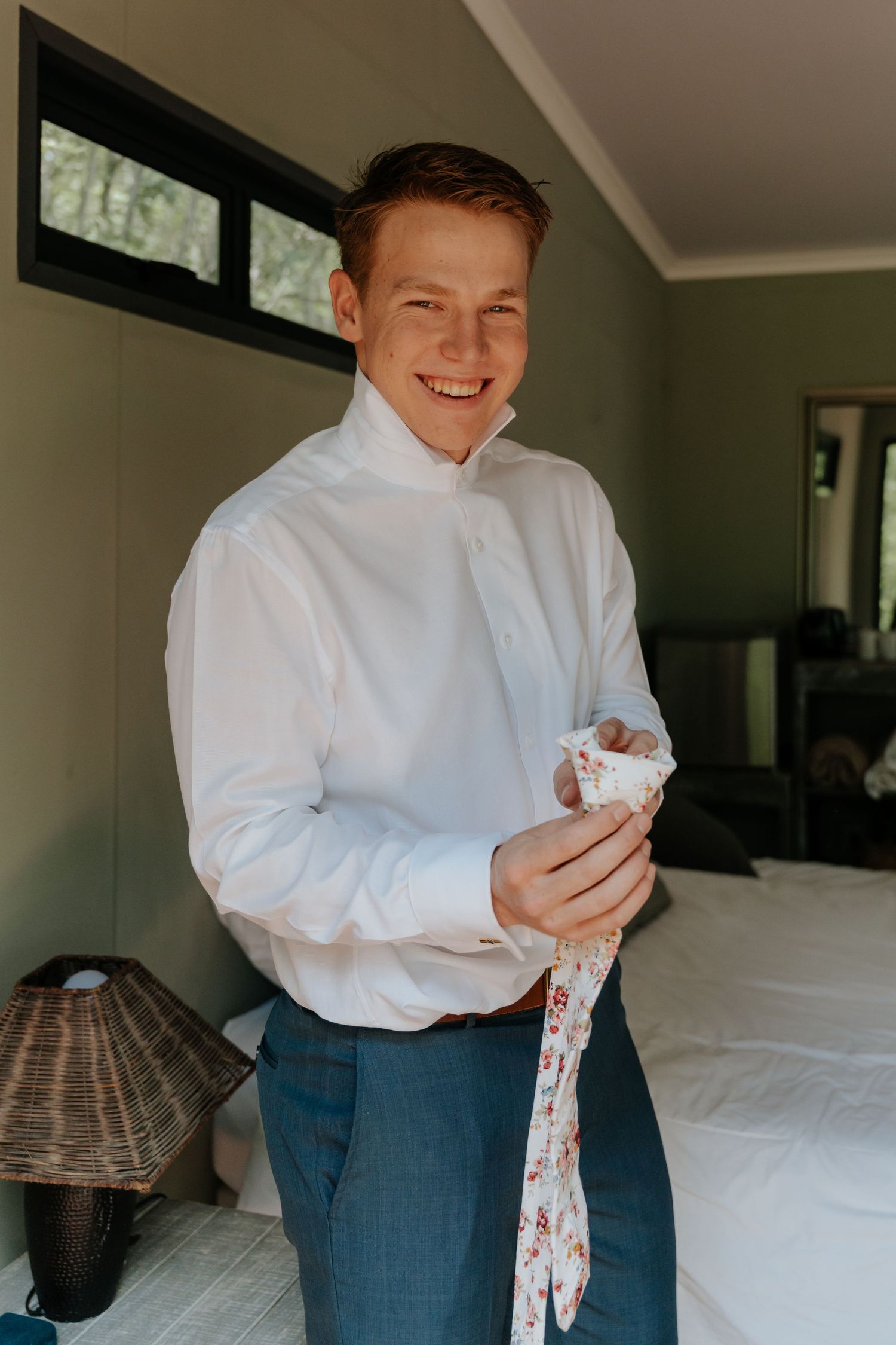 Person in white dress shirt and jeans holding a floral patterned cloth in a bright interior room.