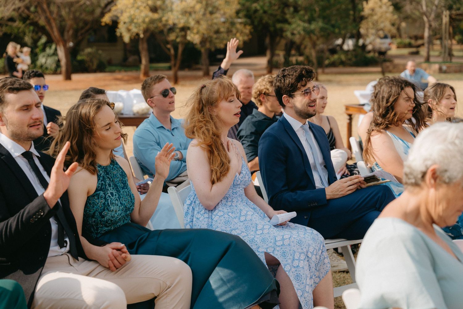 Wedding guests seated in rows watching the ceremony outdoors.