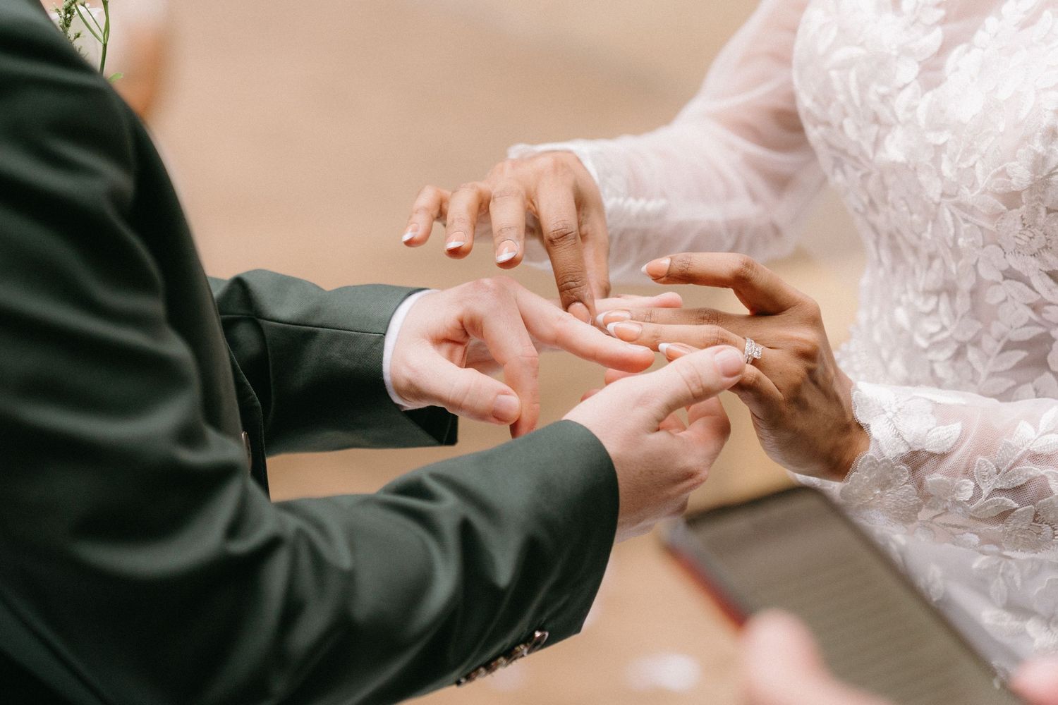Close up shot showing hands exchanging wedding rings during a ceremony.