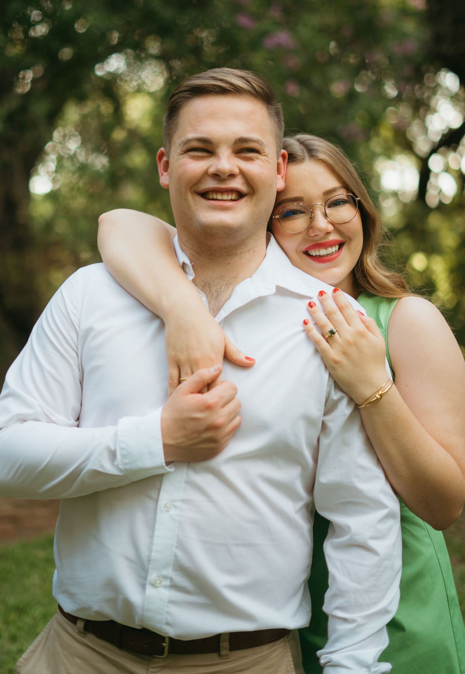 A joyful couple embraces outdoors on a sunny day with bokeh lighting in the background.