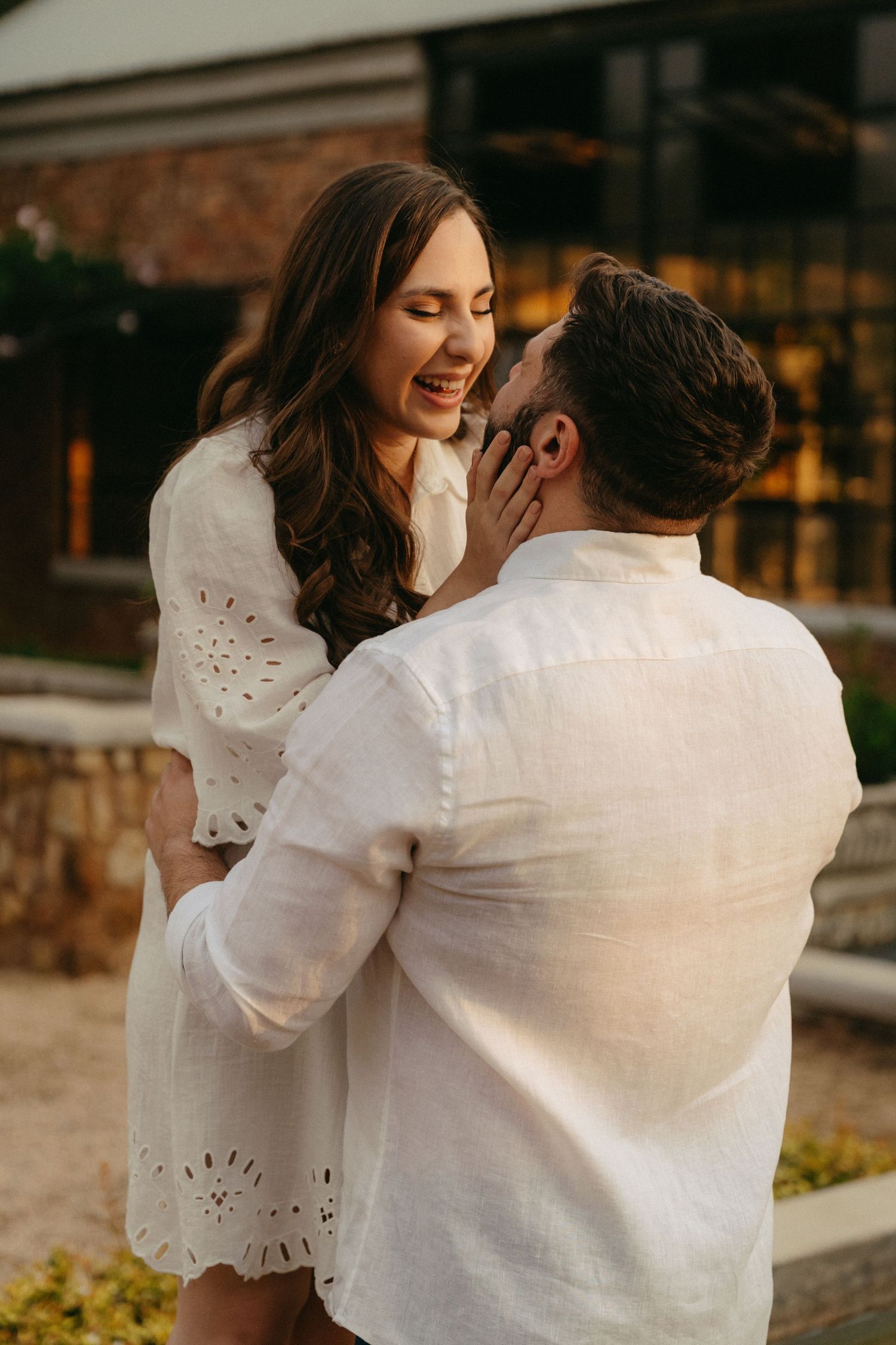 A romantic sequence of a couple in white clothing embracing and sharing tender moments against a rustic backdrop.