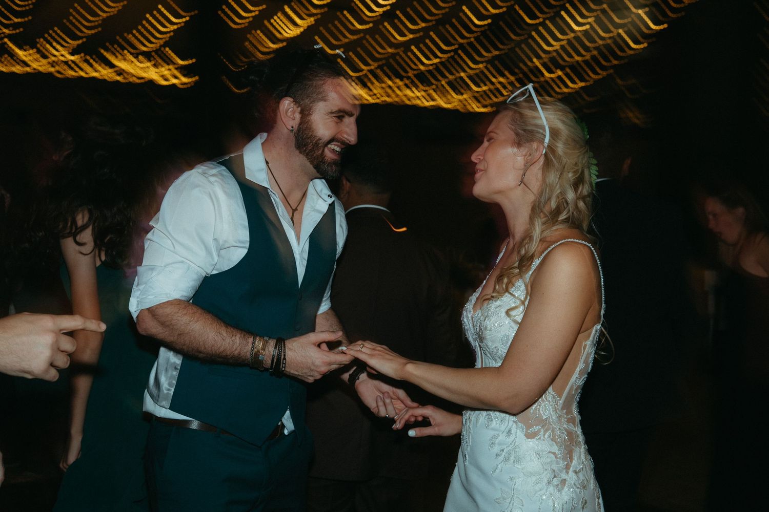 Bride and groom dancing joyfully together at their wedding reception in a warmly lit venue.