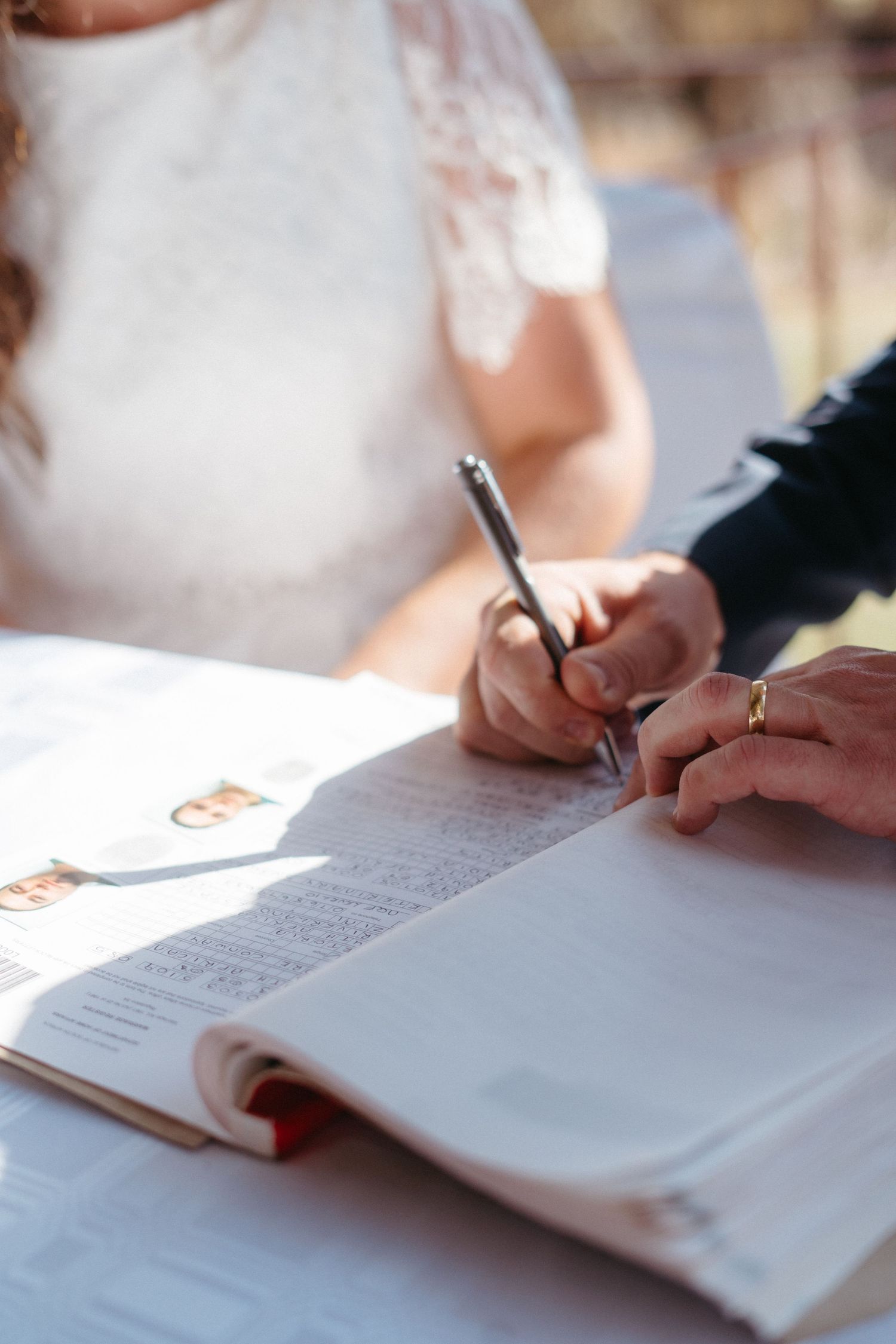 Close-up of signing marriage license documents with pen at wedding ceremony.