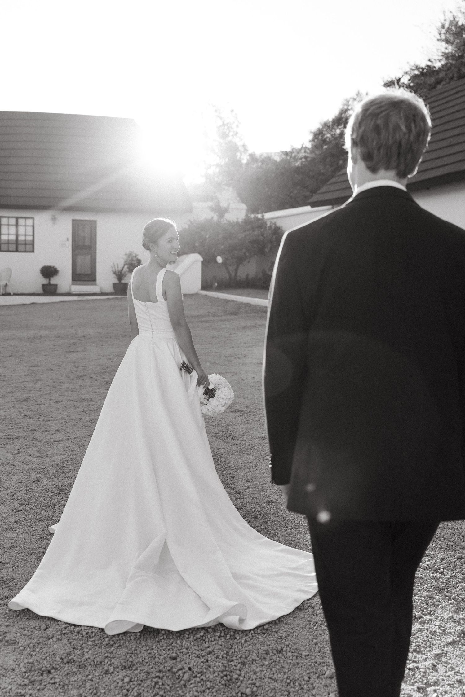 Black and white wedding photo series showing couple in formal attire walking together in outdoor setting at sunset.