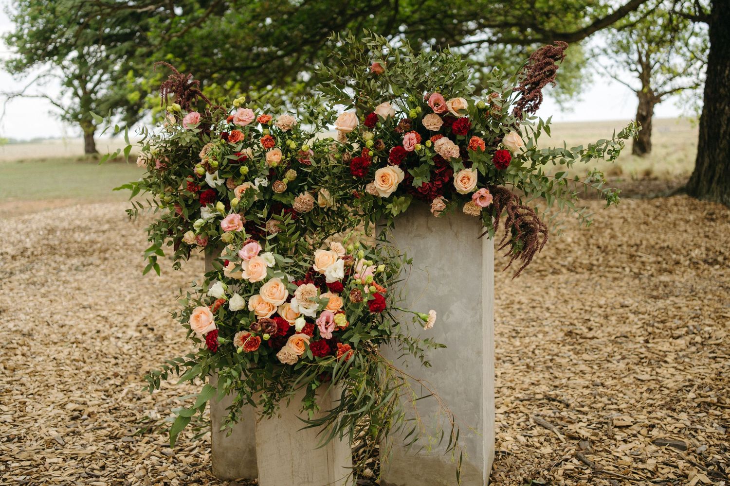 Lush floral arrangement with pink and peach roses on outdoor pillar.