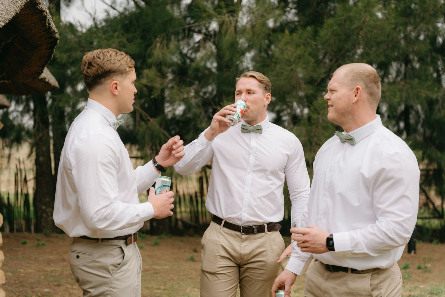 Groomsmen in white shirts and khaki pants gather outdoors before the ceremony.