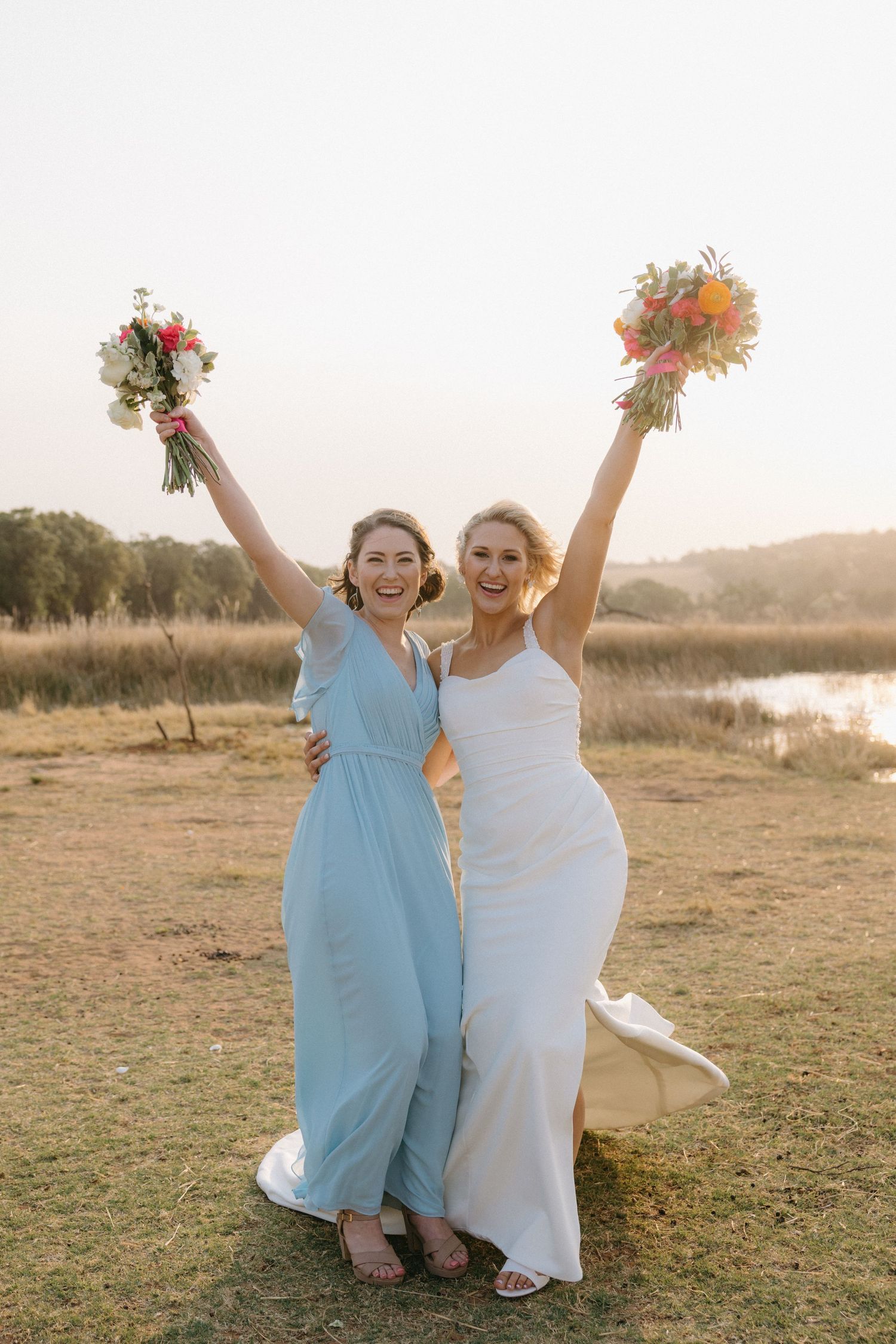 Wedding party celebrating outdoors with joyful poses and light blue bridesmaid dresses.