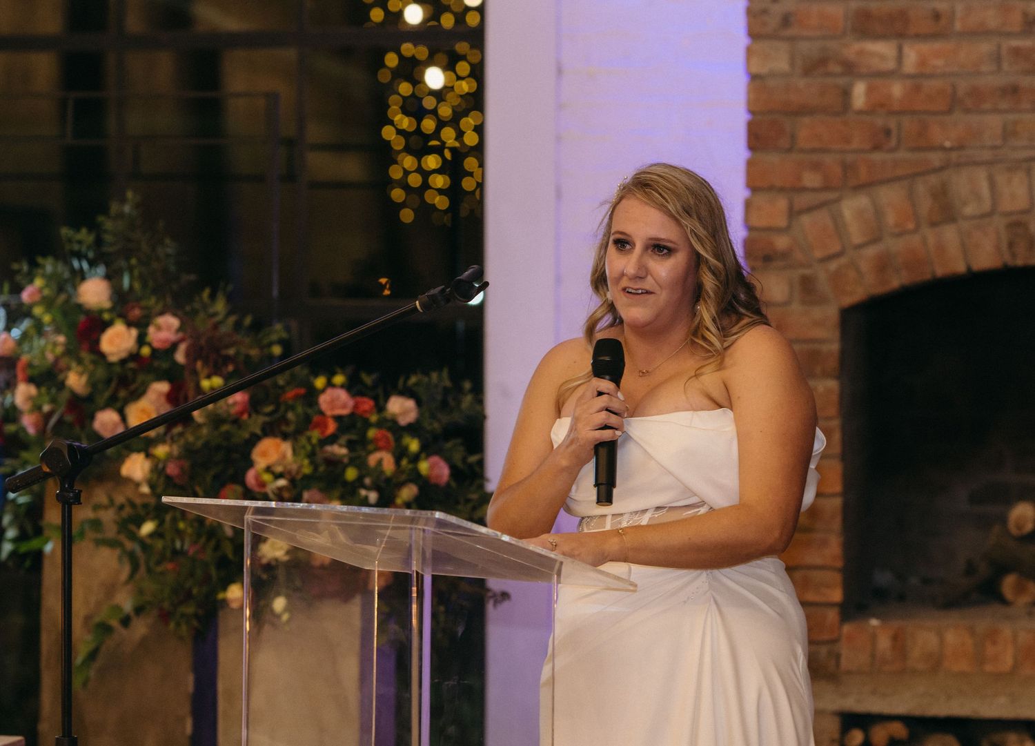 Person in a white wedding dress gives a speech at a podium during the reception.