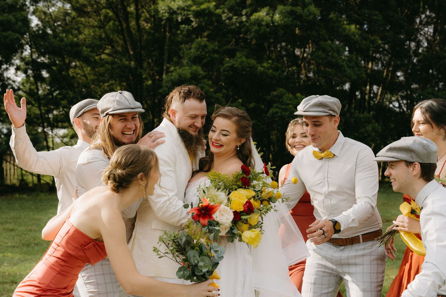 Wedding party celebrates outdoors on a sunny day with vibrant sunflower bouquets.