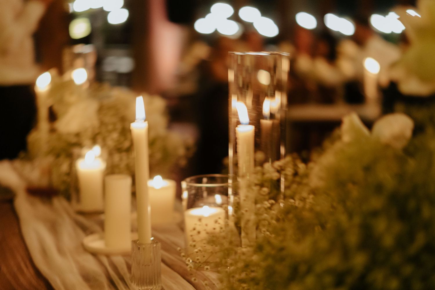 Glowing string lights and candles create a romantic ambiance at an elegant wedding reception.