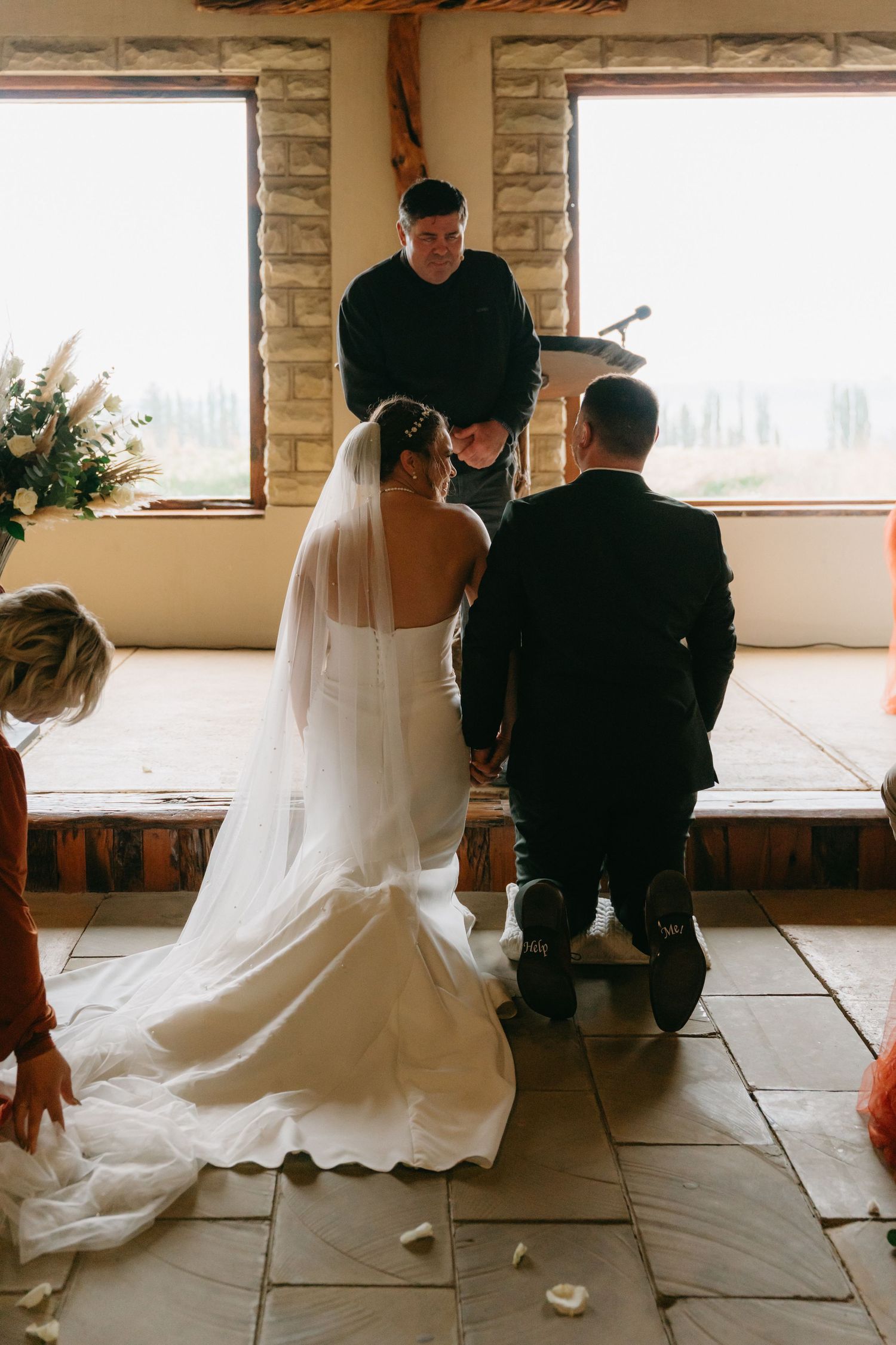 Bride in flowing white dress sitting on stone floor during intimate moment.