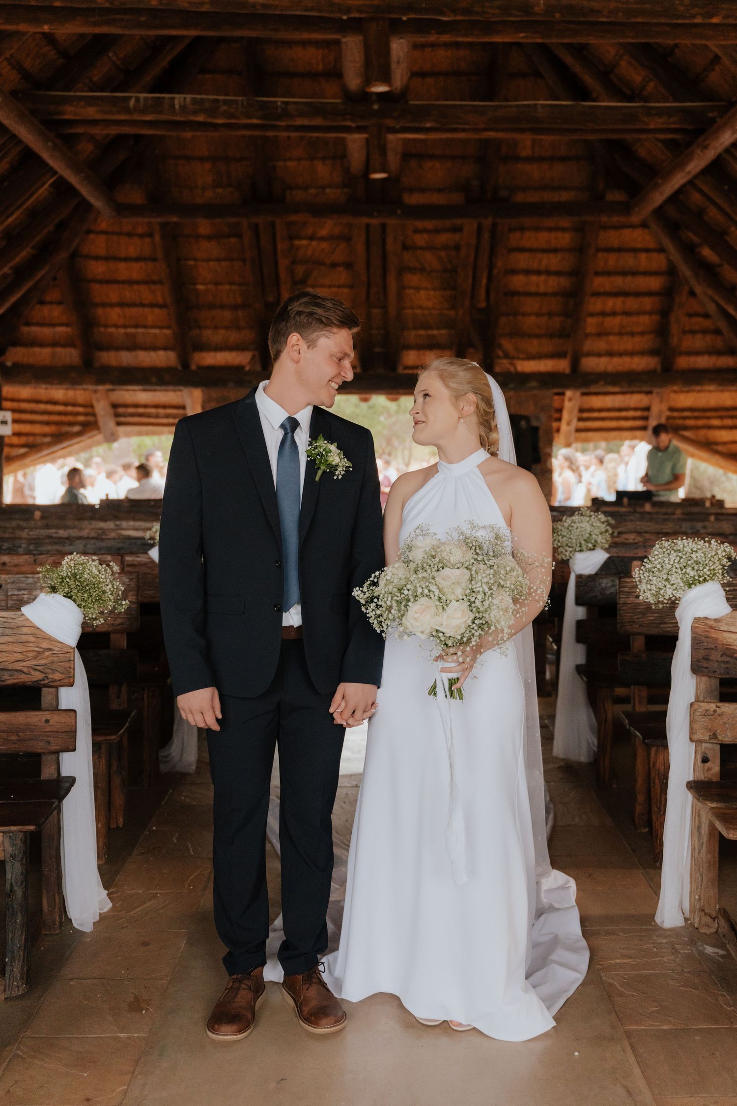 Wedding ceremony in a rustic wooden barn with white decor and baby's breath floral arrangements.