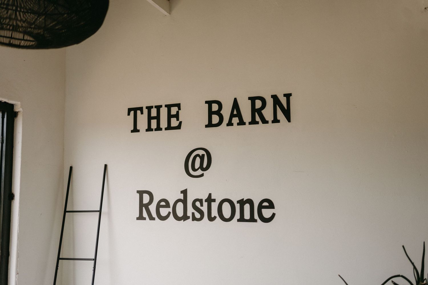 Interior wall signage reading 'THE BARN @ Redstone' with a decorative ladder leaning against the wall.