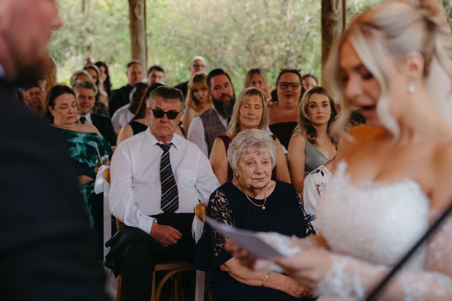Wedding guests gather around and watch attentively during an emotional ceremony moment.