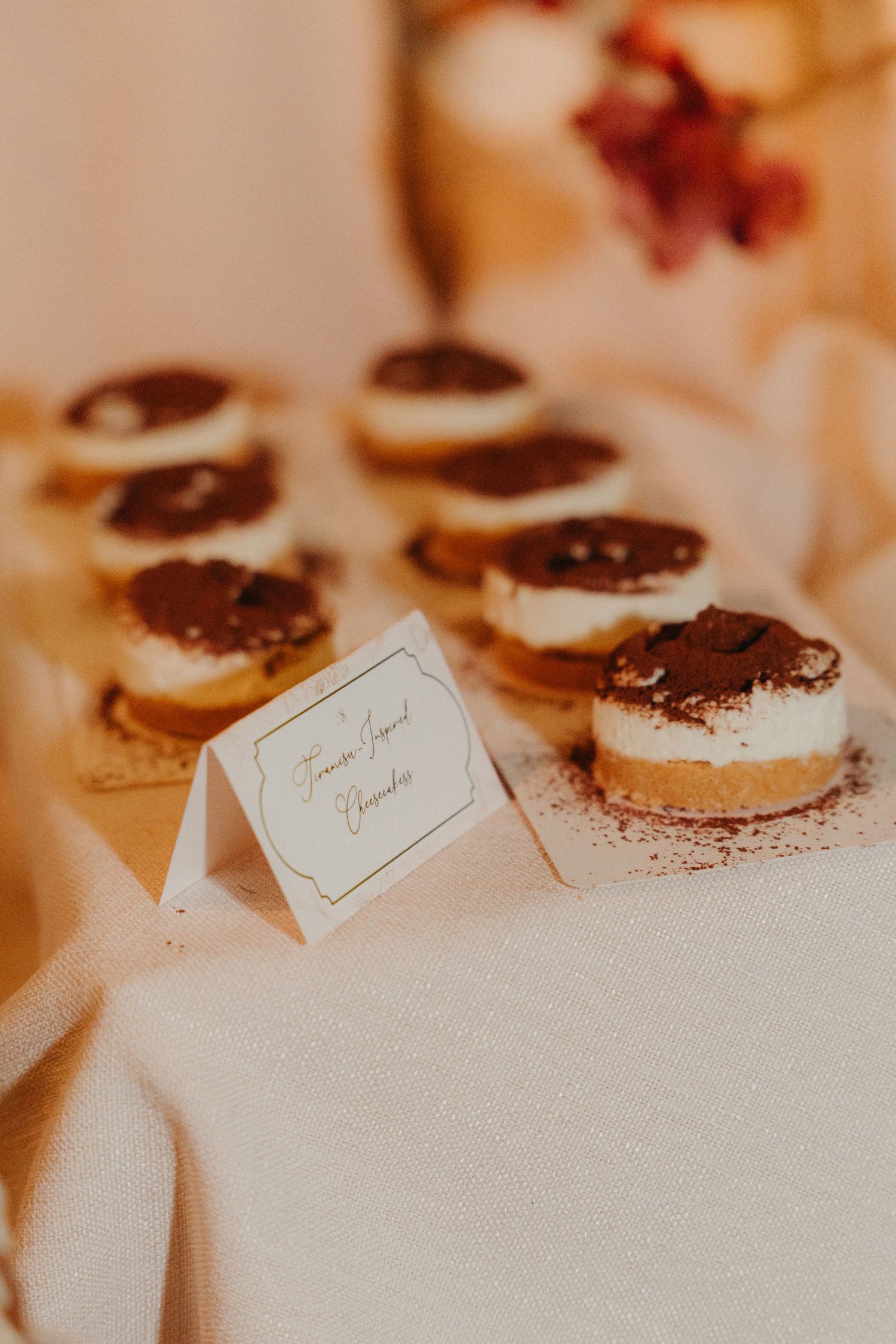 Elegant tiramisu desserts with cocoa dusting displayed on a white linen table with a decorative label card.