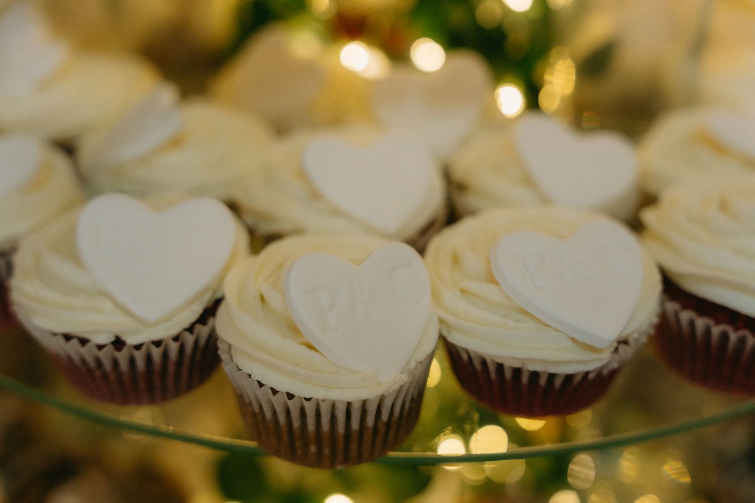 Elegant display of white-frosted cupcakes arranged on a glass platter at a wedding reception.