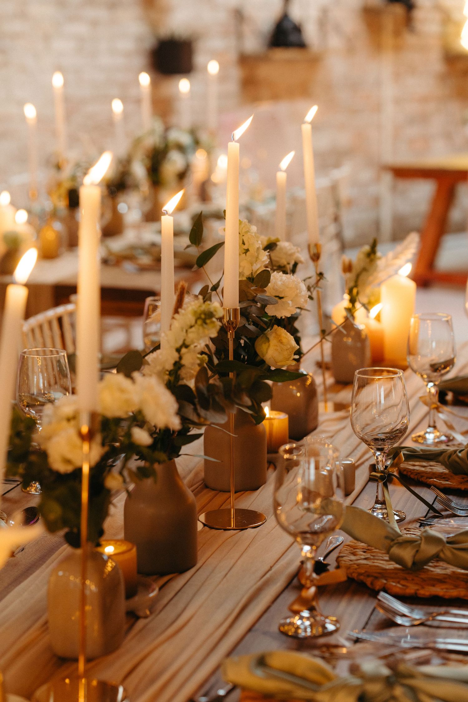 Elegant table setting with glowing candles, white flowers, and wine glasses creating a romantic ambiance.