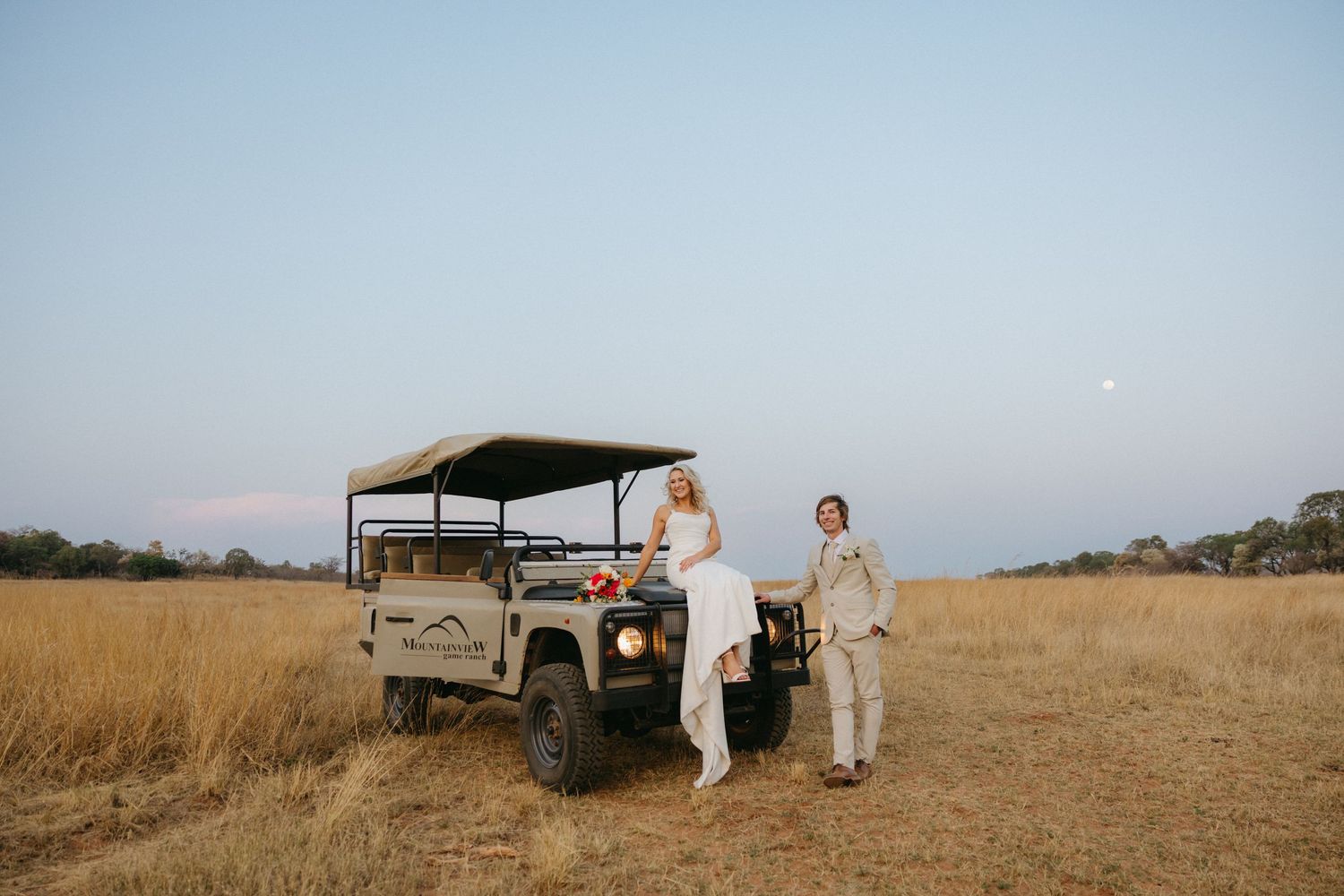 Vintage truck parked in a golden field during a rustic outdoor wedding celebration.