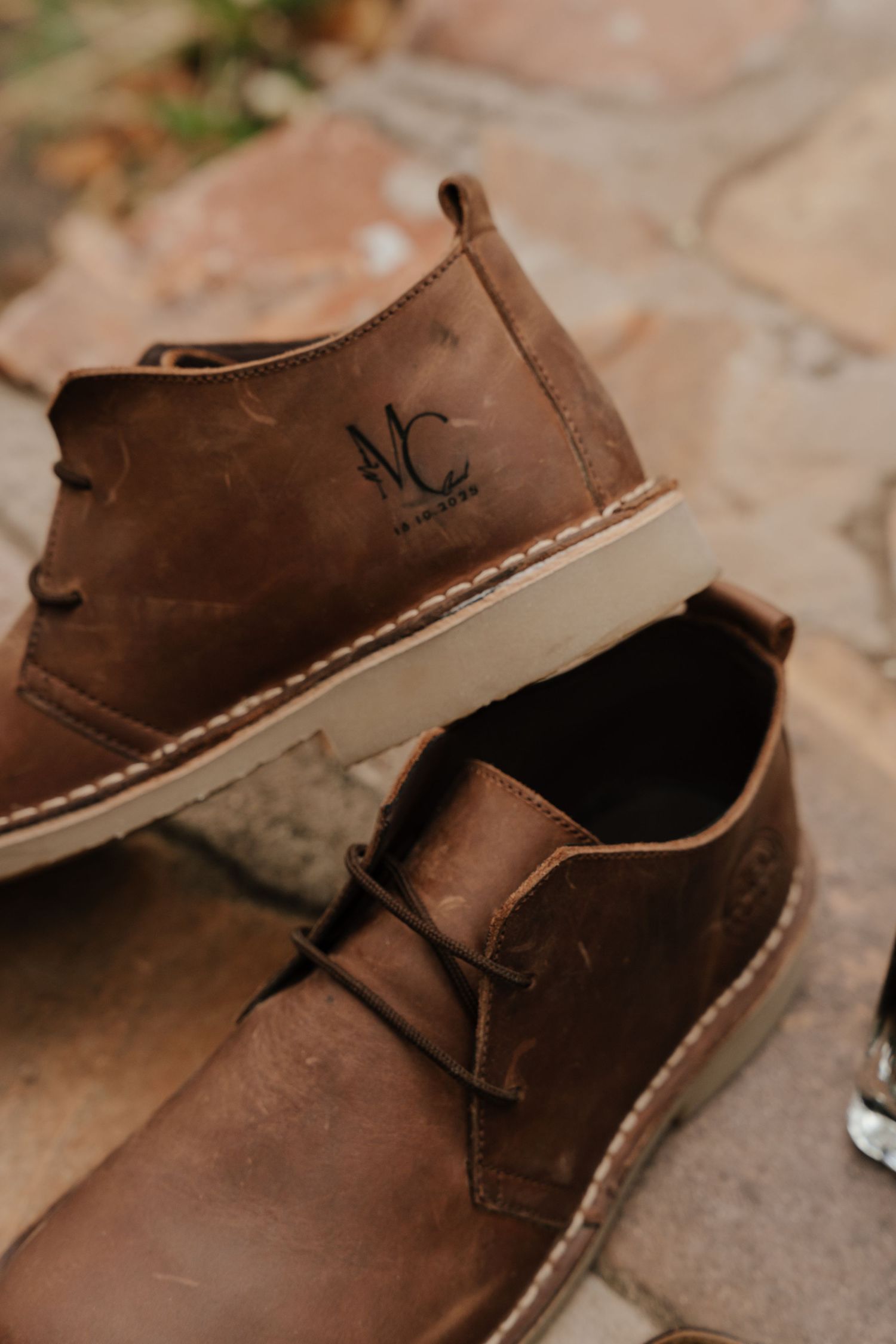 Brown leather desert boots arranged on a textured stone surface in natural lighting.