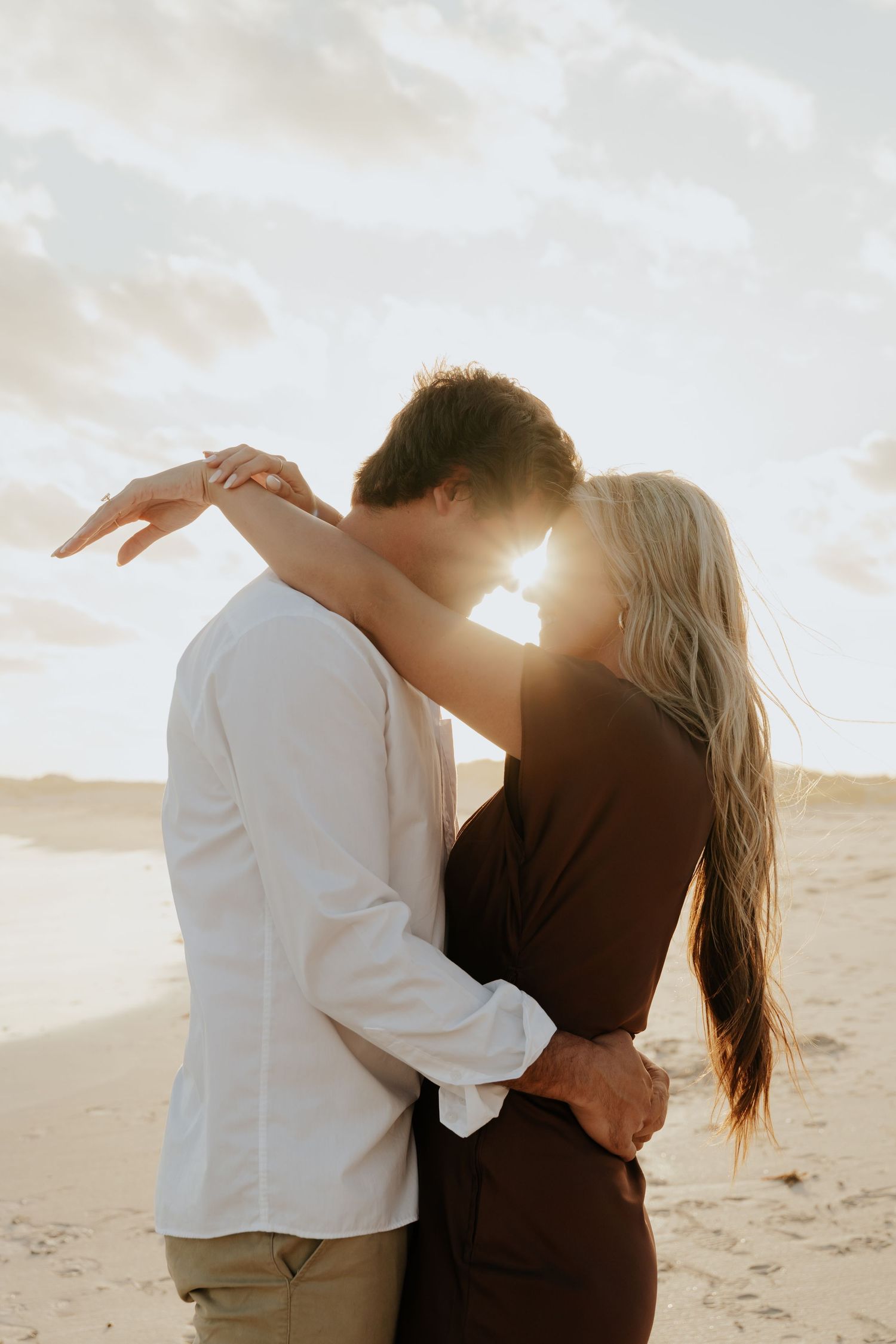 Couple sharing a kiss backlit by golden sunset light on a Western Cape beach during engagement photoshoot.