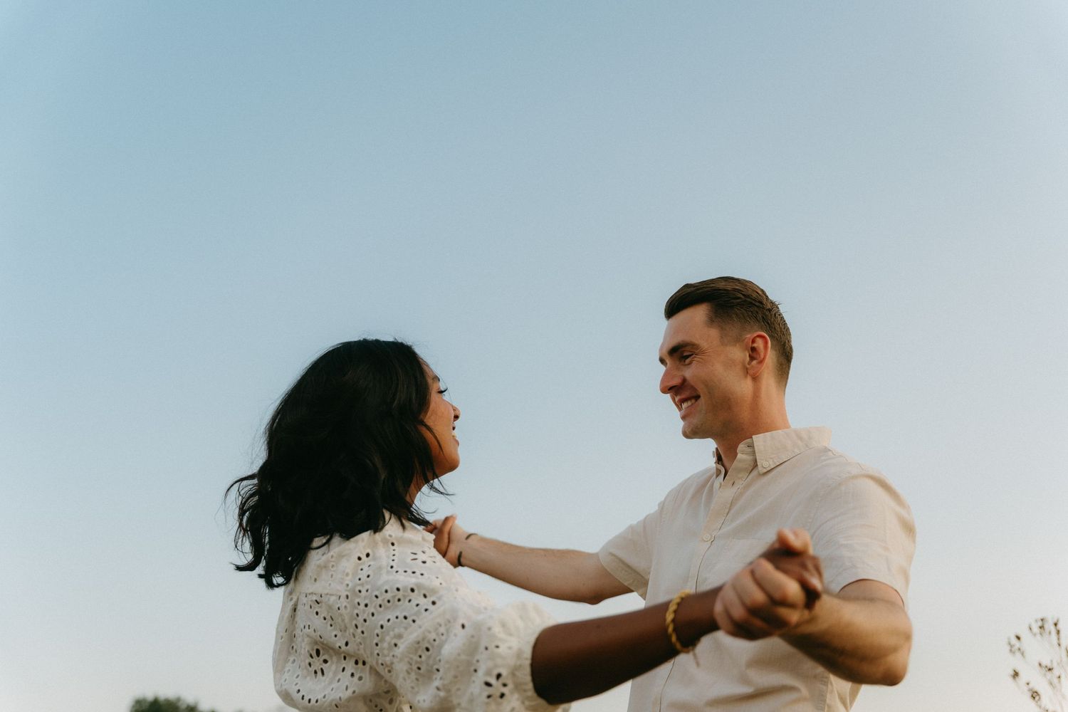 Couple dancing and smiling joyfully together against a clear blue Johannesburg sky at sunset.