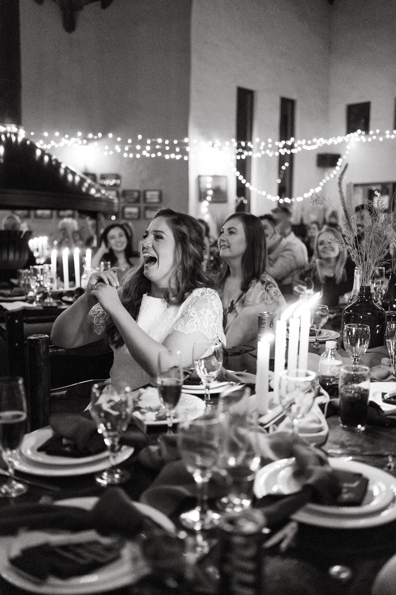 A candlelit reception dinner scene with guests celebrating under string lights.