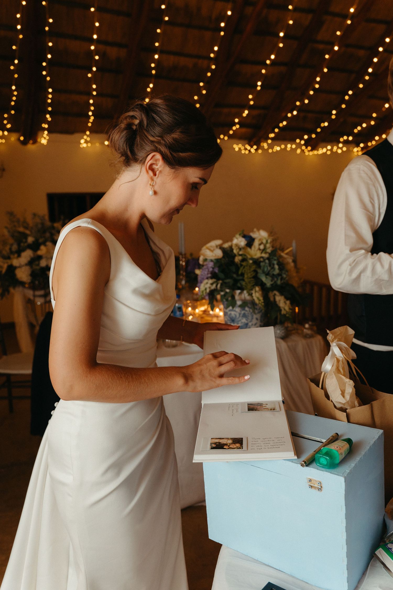 A series of photos showing someone in white writing on a light blue box under string lights.