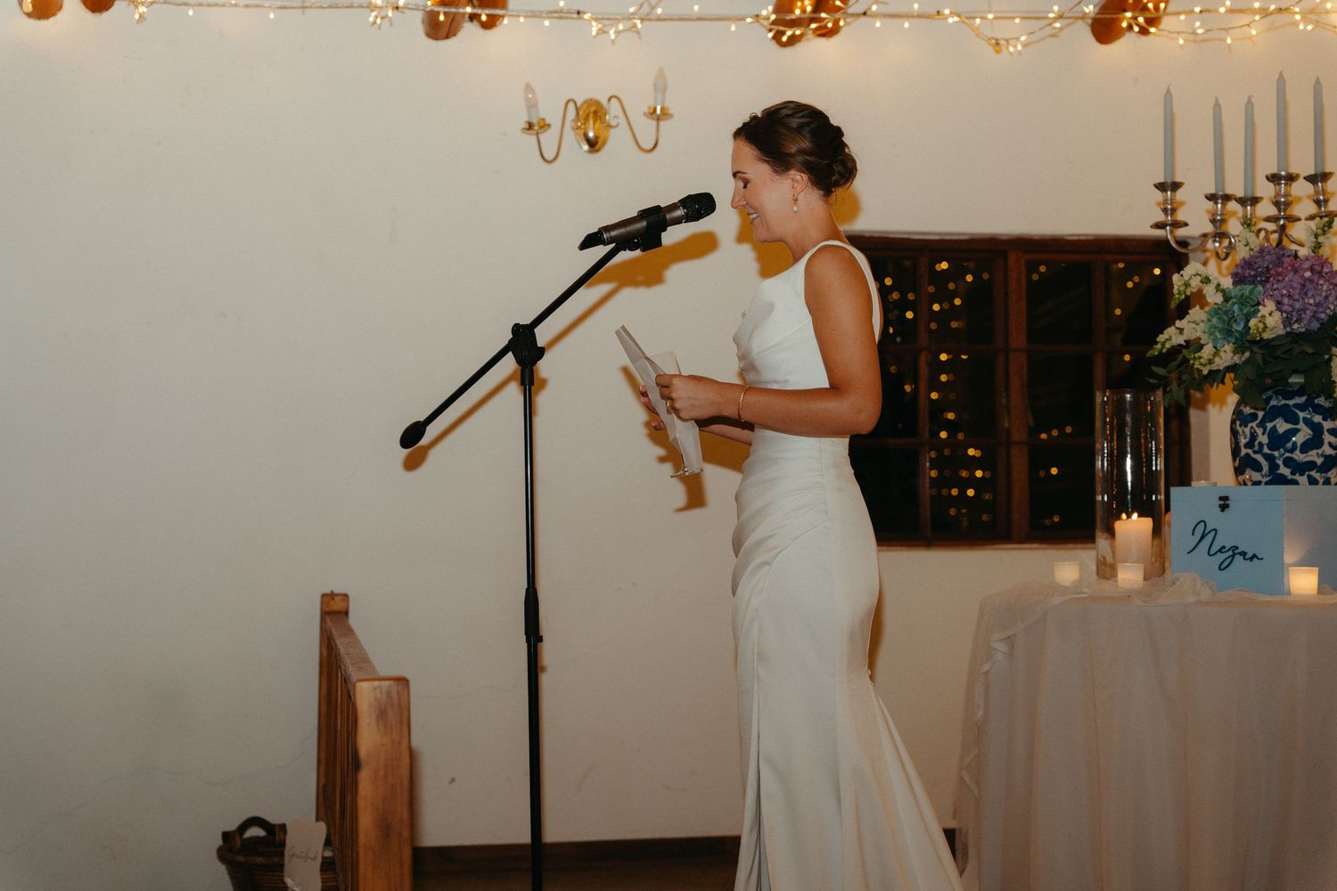 Romantic wedding reception venue decorated with warm string lights and elegant table settings.