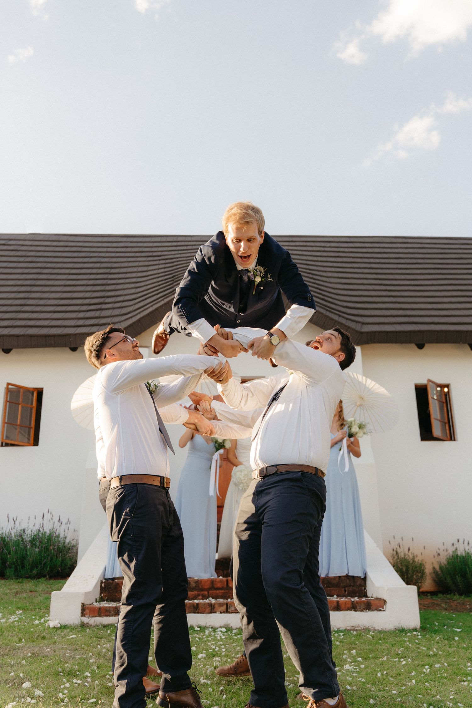 A playful series of photos showing groomsmen dipping and dancing together outdoors against a white building.